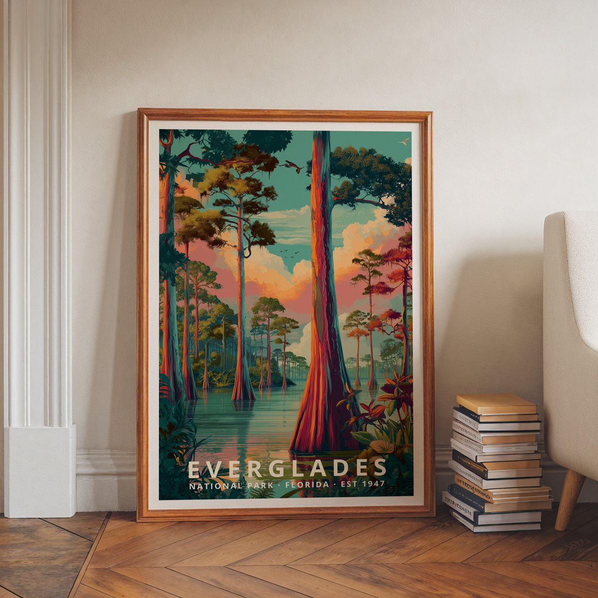 Everglades National Park retro travel poster in a wood frame, leaning against a wall beside a stack of books and an armchair