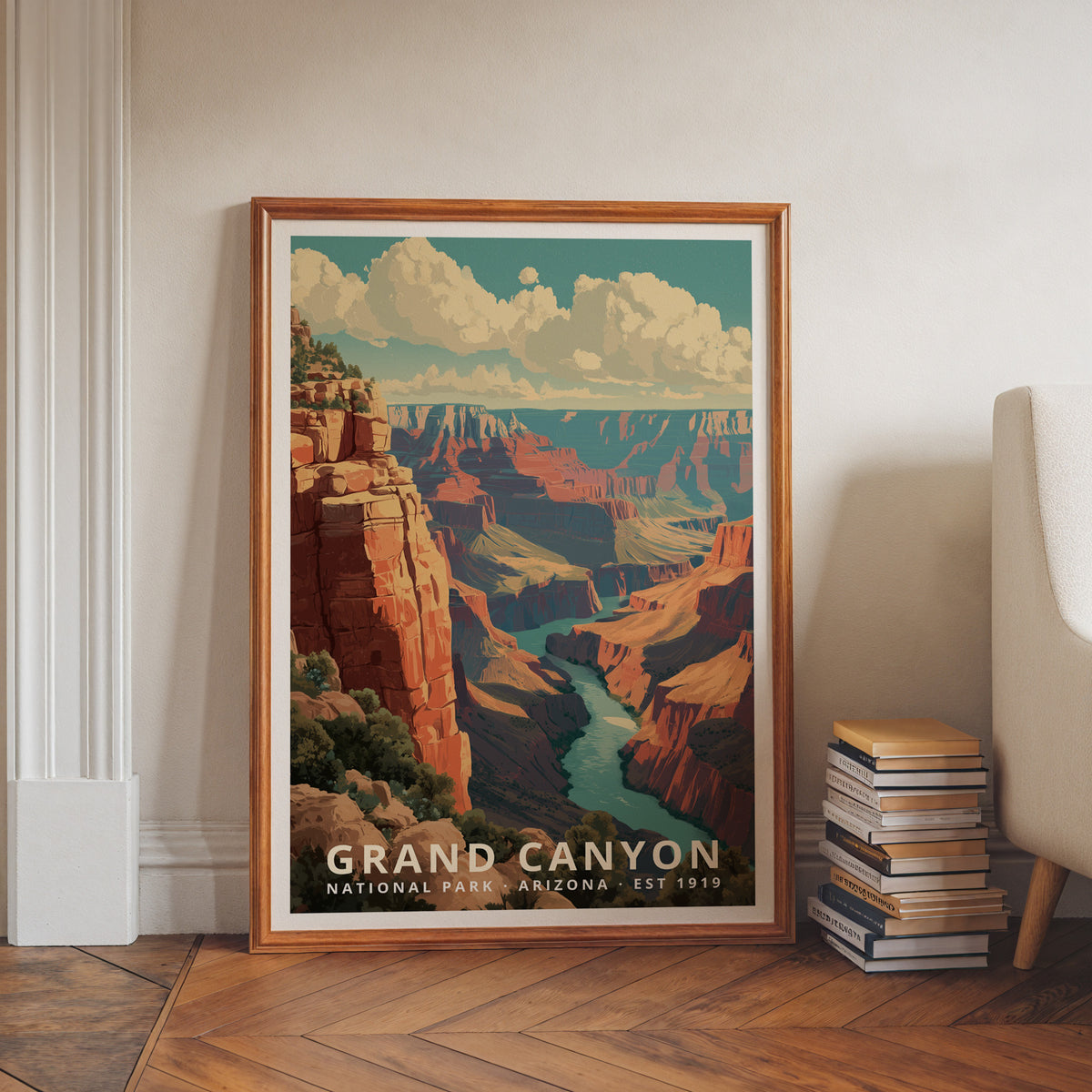 Grand Canyon National Park retro travel poster in a wood frame, leaning against a wall beside a stack of books and an armchair