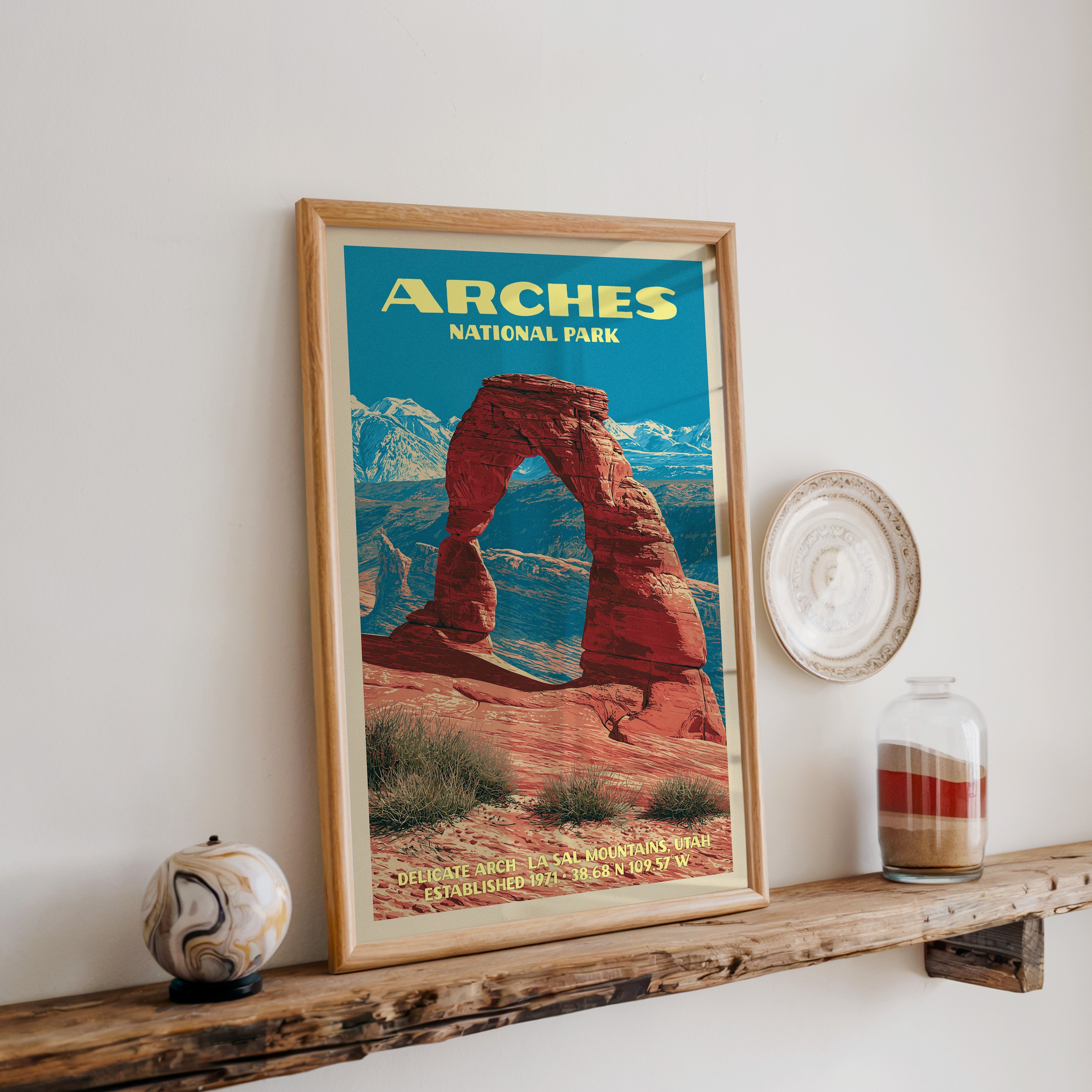 Arches Delicate Arch print in oak, leaning on a reclaimed wood ledge with a marbled sphere and sand jar