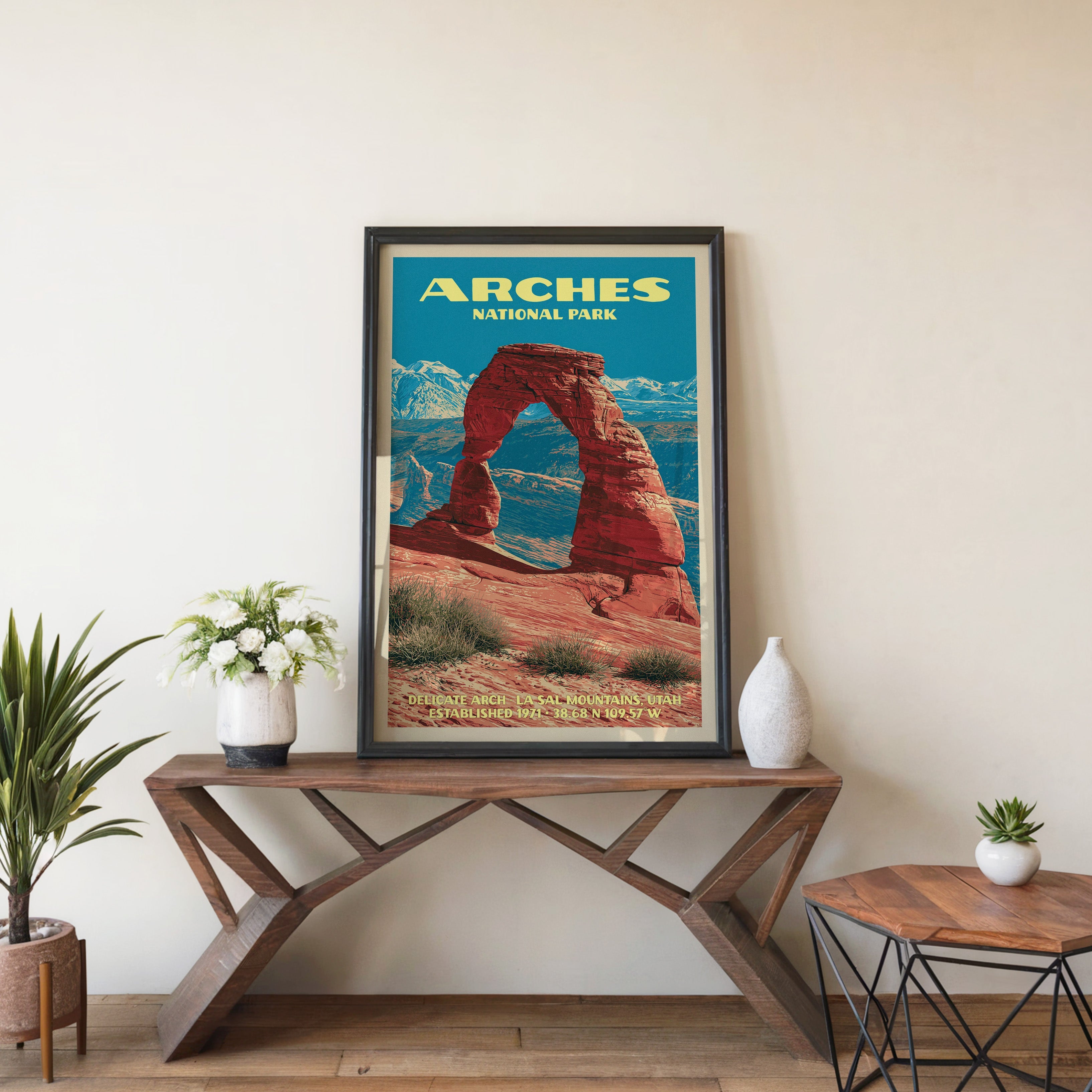 Arches Delicate Arch wall art in black, leaning on a walnut console with white anemones and a vase