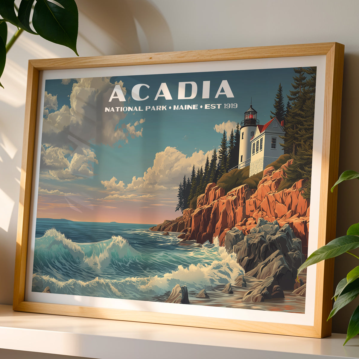 Acadia National Park wall art print in a light oak frame, leaning on a white shelf in warm sunlight beside a monstera plant