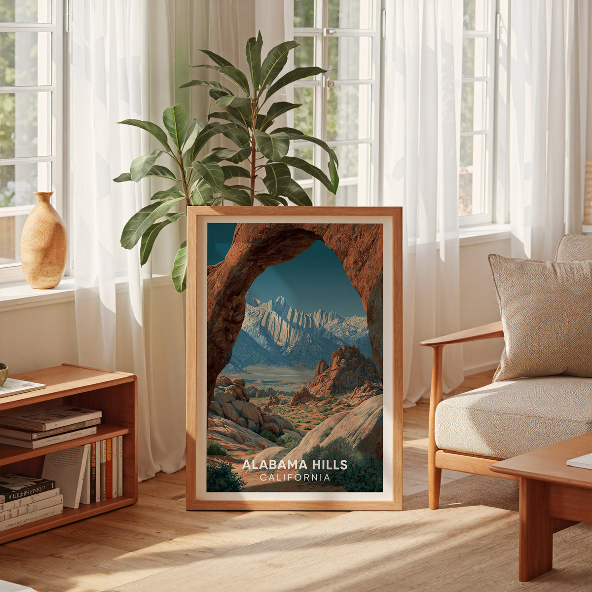 Alabama Hills print in an oak frame beside a tall sheer-curtained window, low bookshelf, rubber plant and cream armchair