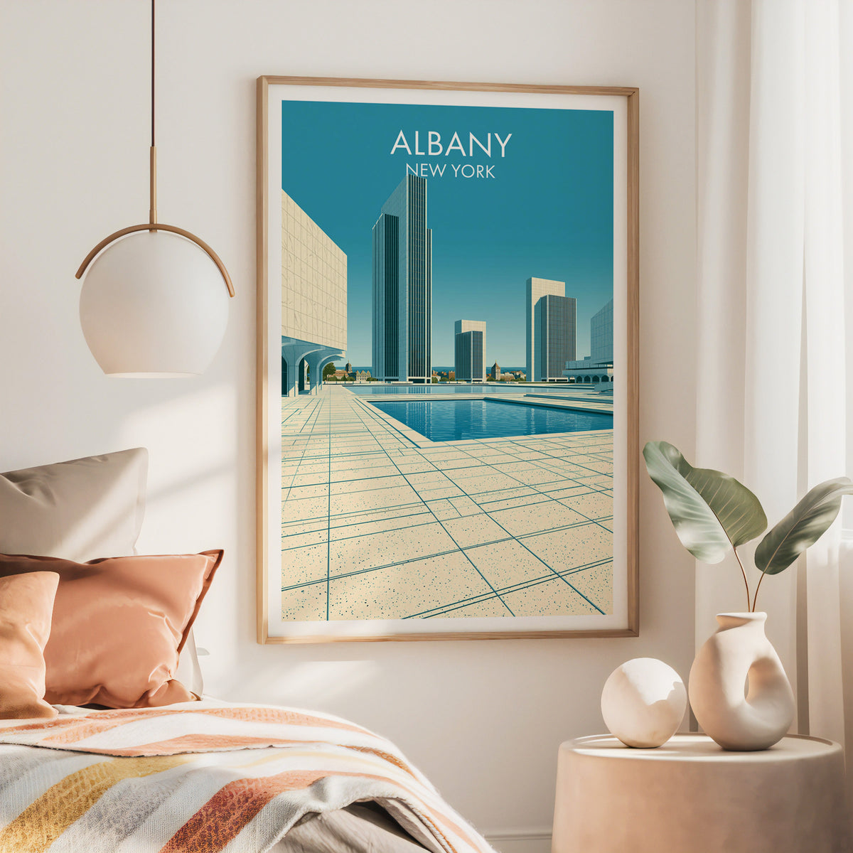 Empire State Plaza poster in a large oak frame above a bed with rust bedding and a brass pendant light.