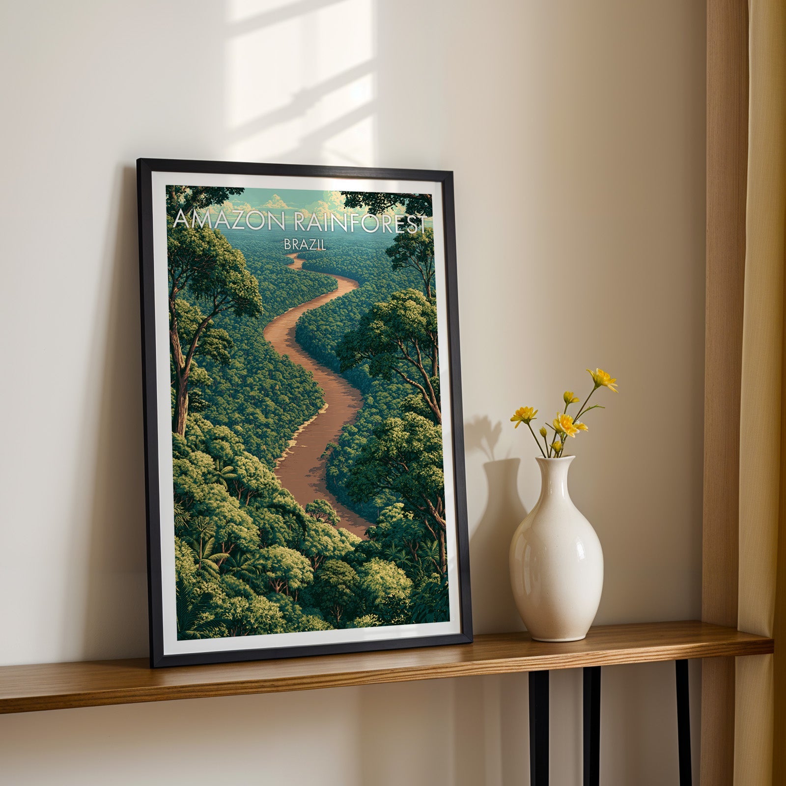 Brazil rainforest wall art in a black frame on a narrow wood shelf with yellow daisies in a white vase