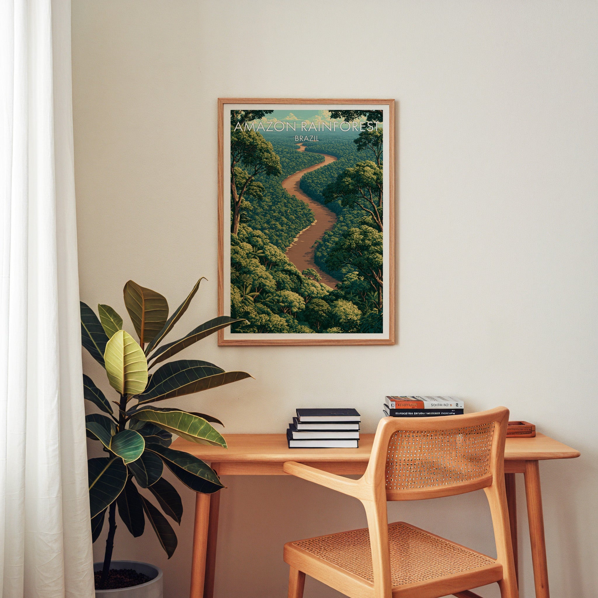 Amazon River travel art in an oak frame above a wood desk with a cane chair, books and a rubber plant