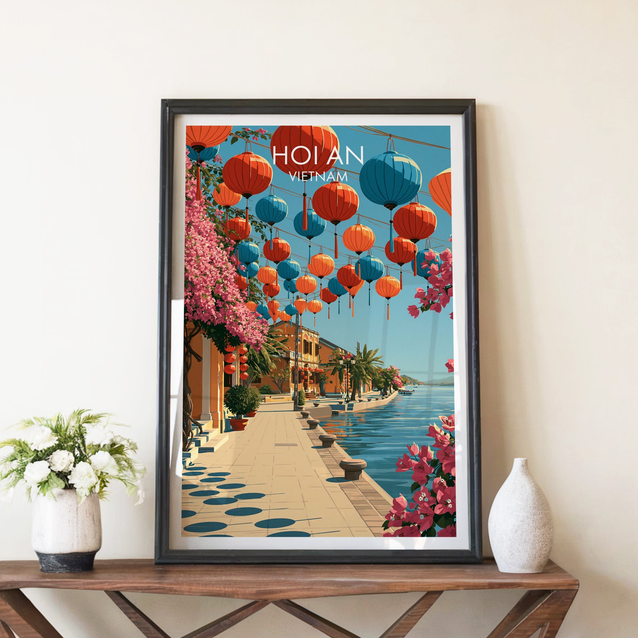 Hoi An Vietnam travel poster in a black frame on a wooden console table with white flowers and vase