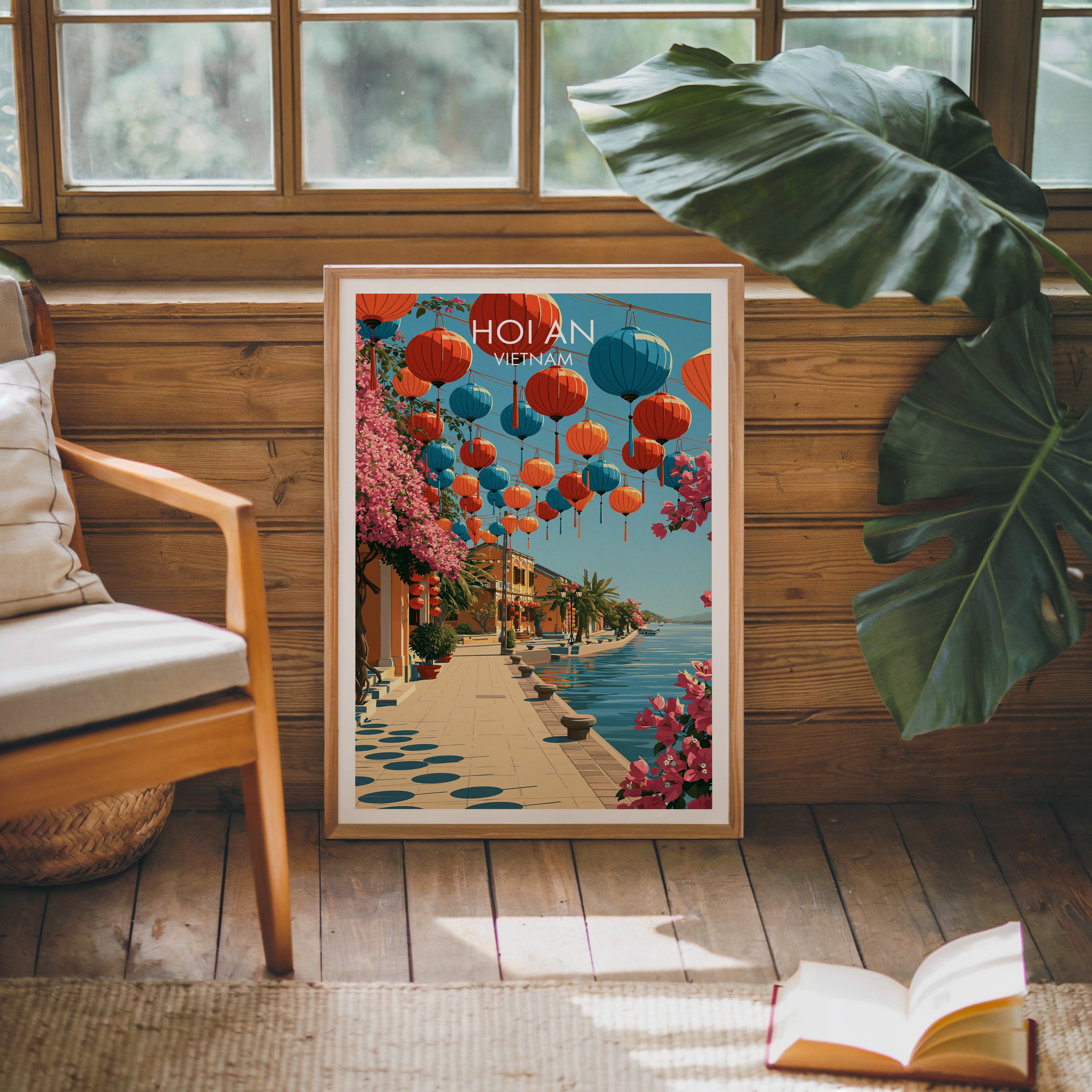 Framed Hoi An Vietnam poster leaning against a timber cabin wall with monstera leaves and an open book