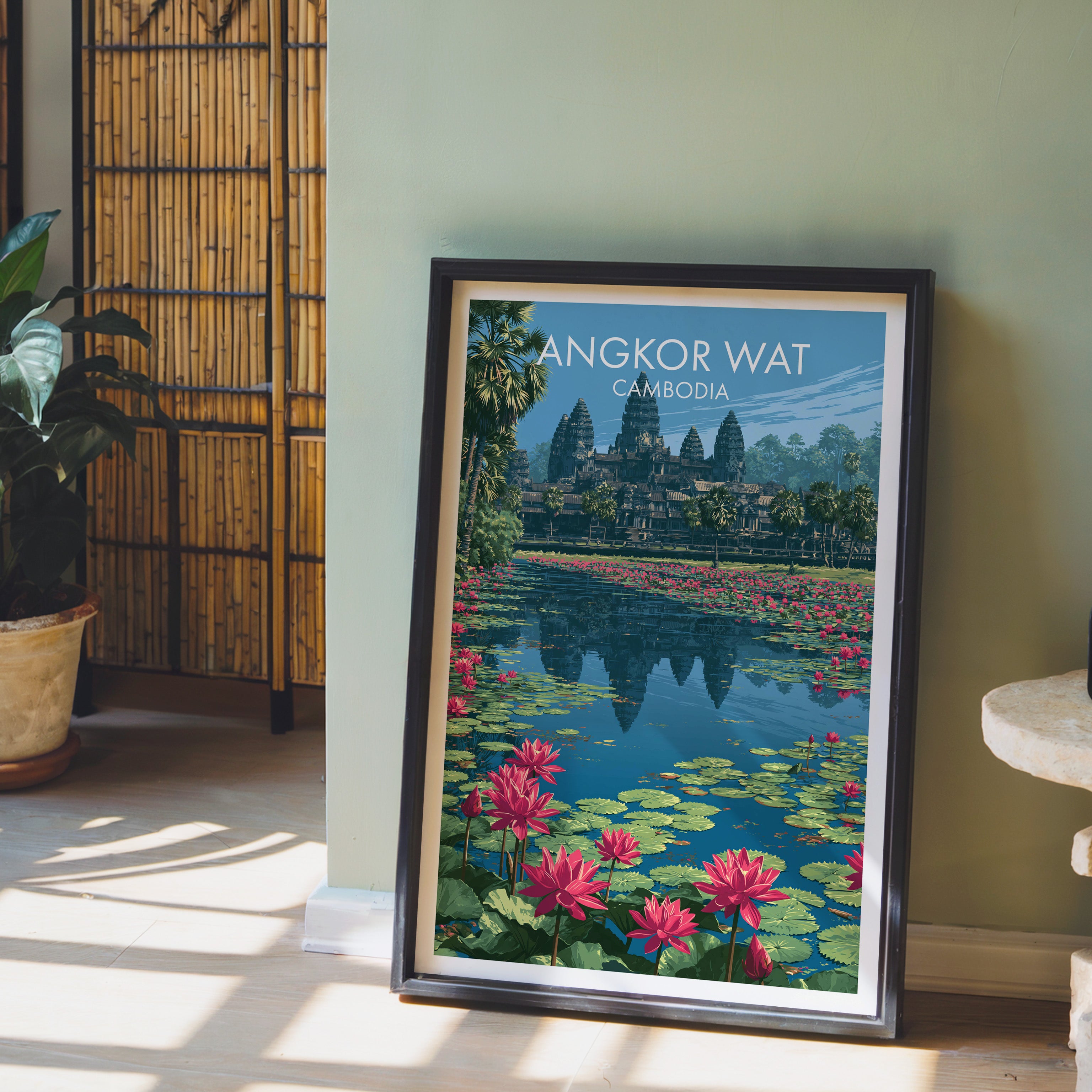 Angkor Wat Cambodia wall art in a black frame leaning against a sage green wall beside a bamboo screen