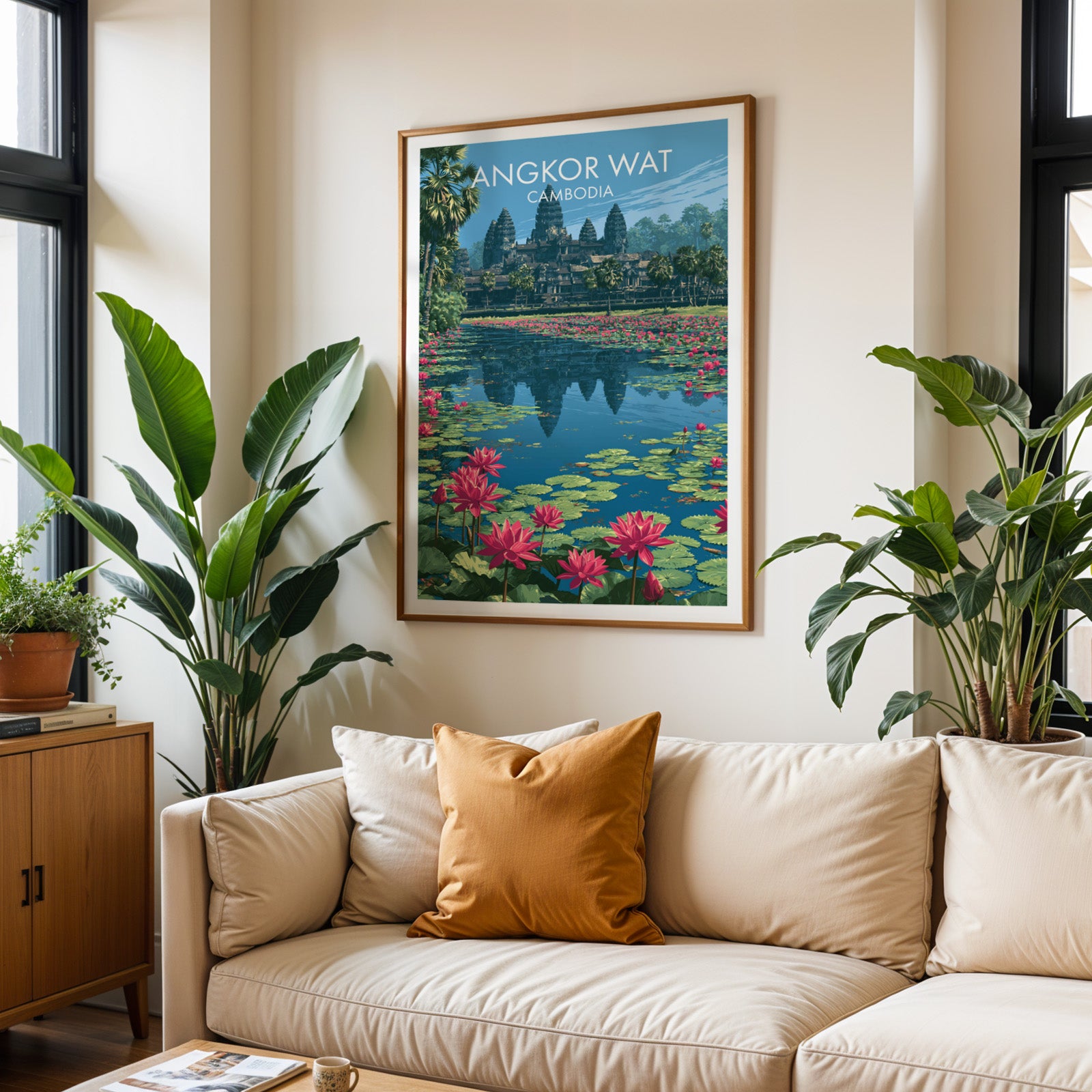 Framed Angkor Wat Cambodia wall art hanging above a cream sofa in a bright living room with tropical plants