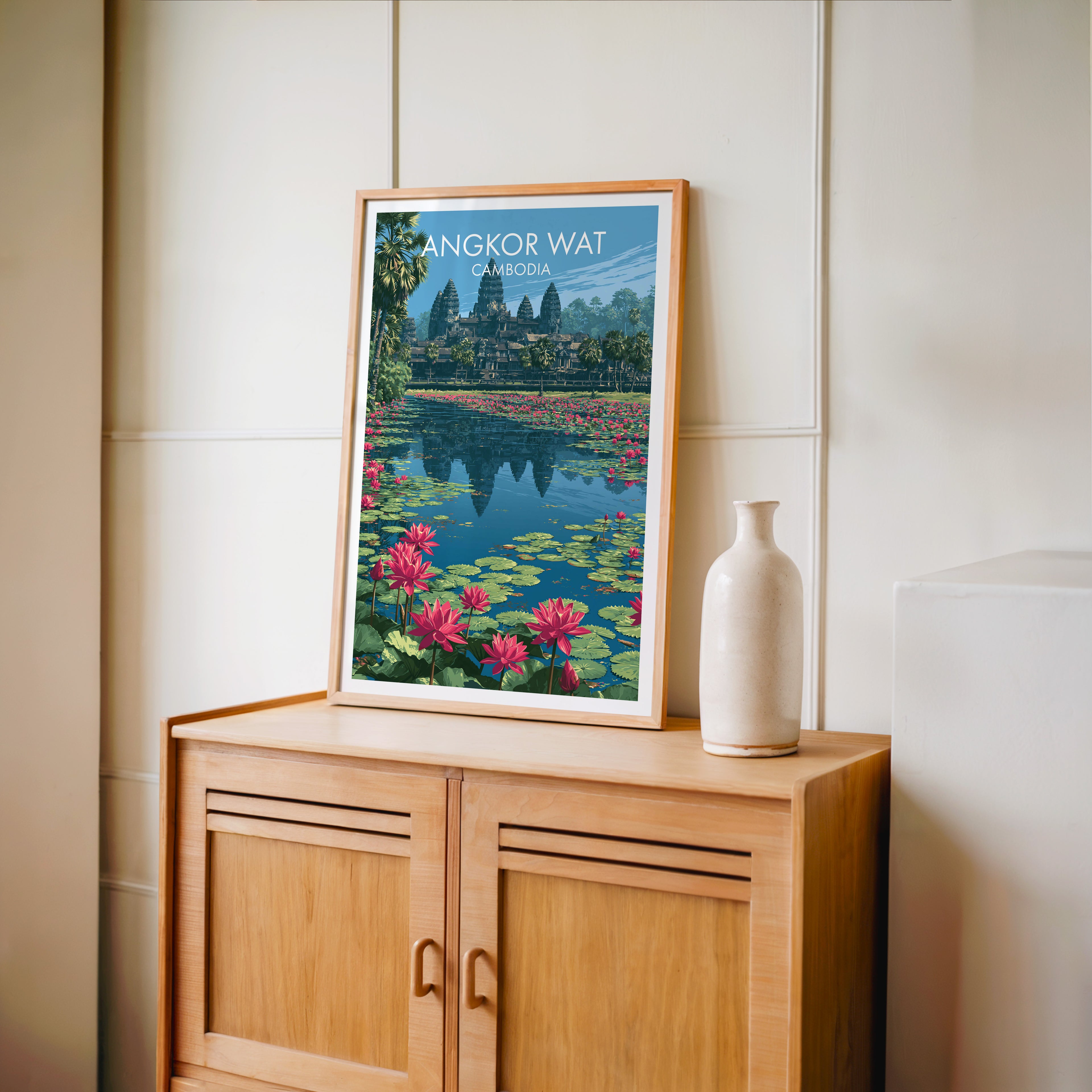 Small Angkor Wat Cambodia travel poster in an oak frame on a mid-century sideboard with a ceramic vase