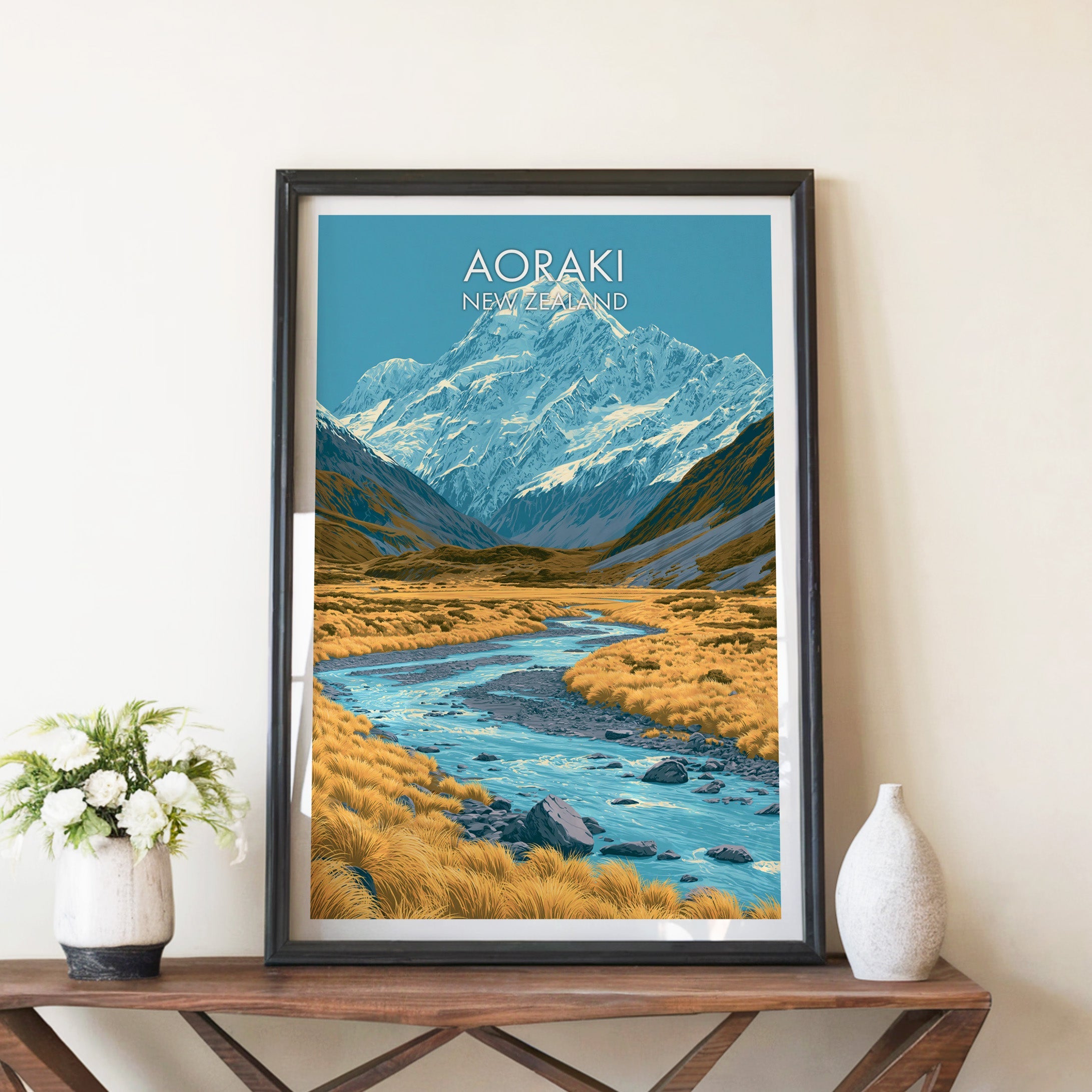 Aoraki poster in a black frame on a walnut console with white peonies and a tall ceramic vase