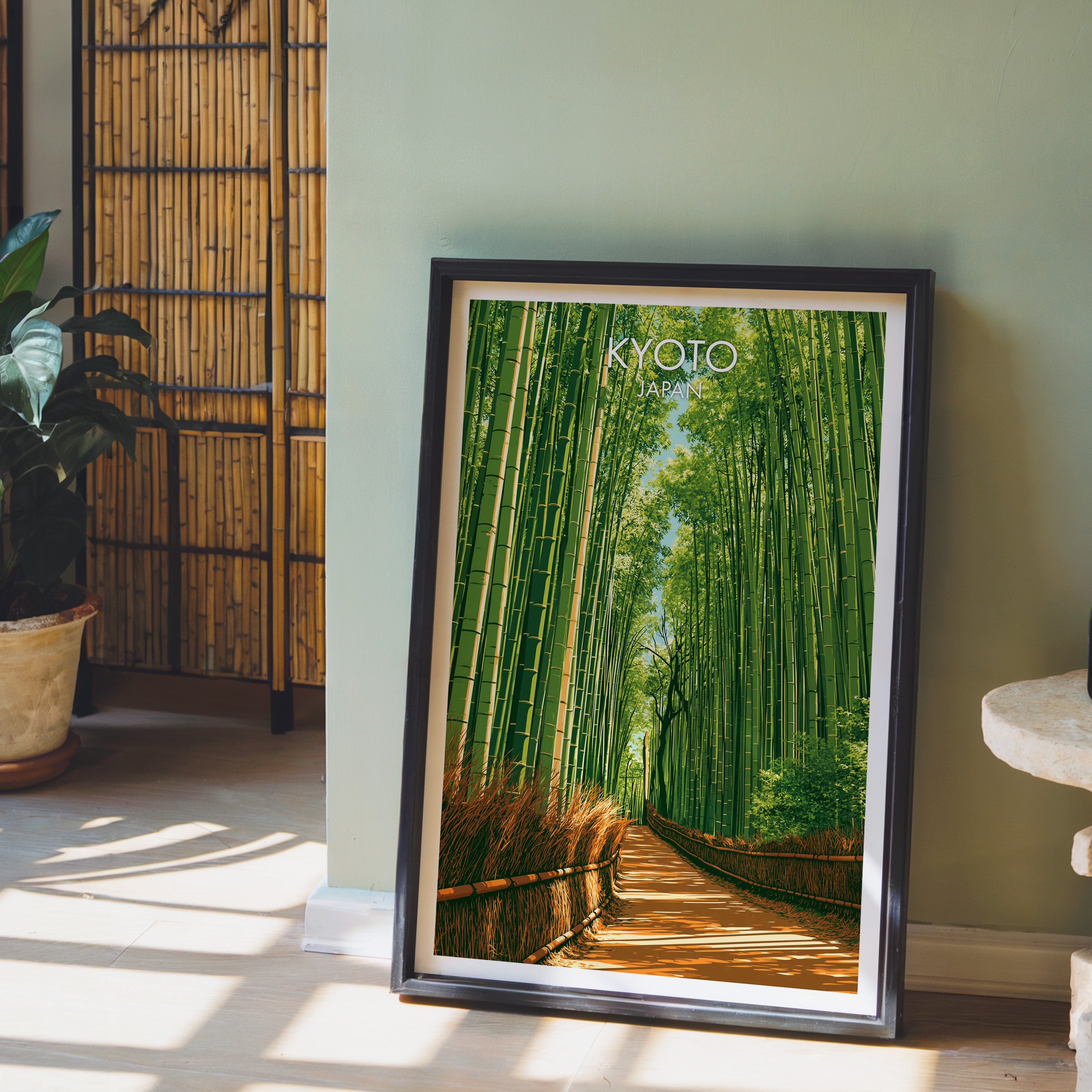 Arashiyama Bamboo Forest Kyoto wall art in a black frame leaning against a sage green wall beside a bamboo screen