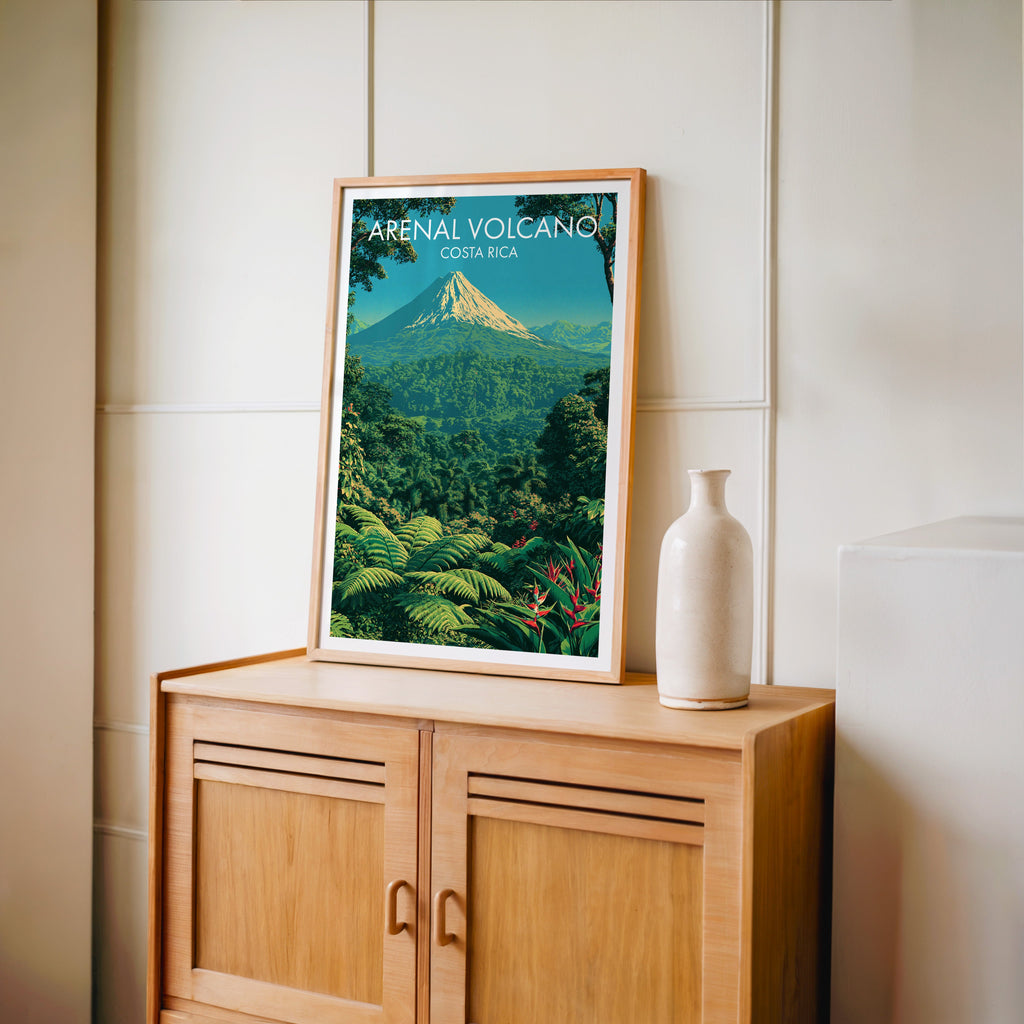 Red heliconia and broad leaves in an oak frame on a light oak cabinet, cream panelled wall and a vase