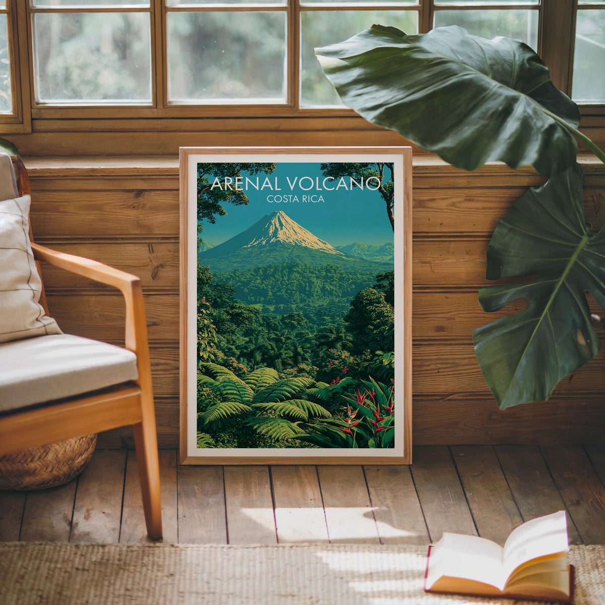 Arenal poster in an oak frame leaning on a pine cabin wall, wooden armchair, monstera leaf and jute rug