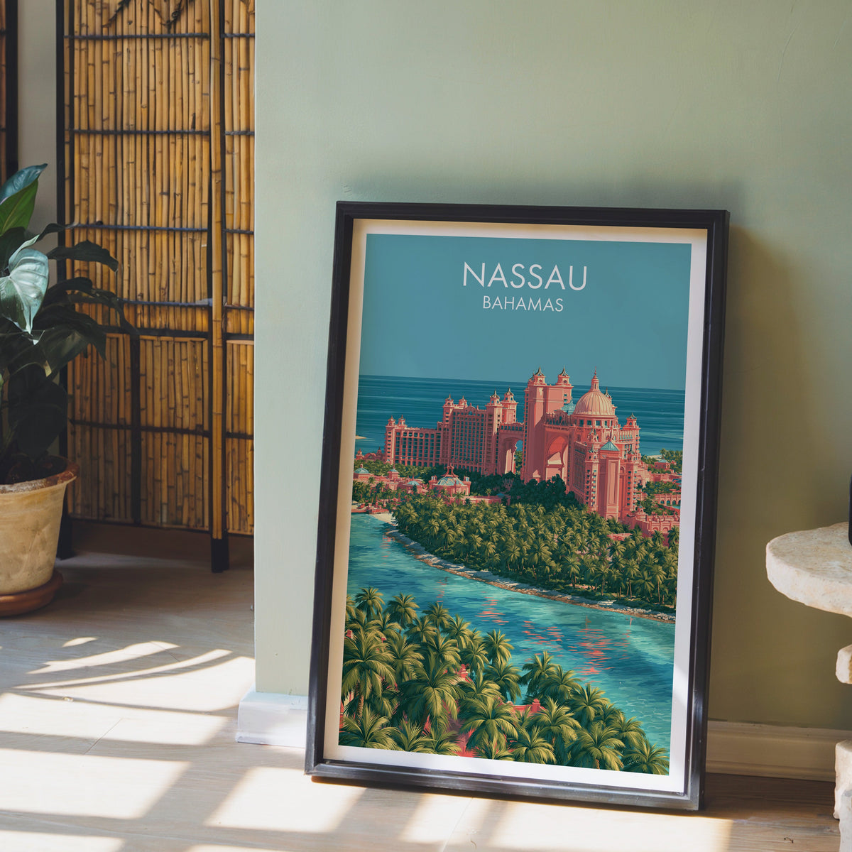Turquoise Bahamian water in a black frame leaning on pale wood floor by a sage wall and bamboo screen