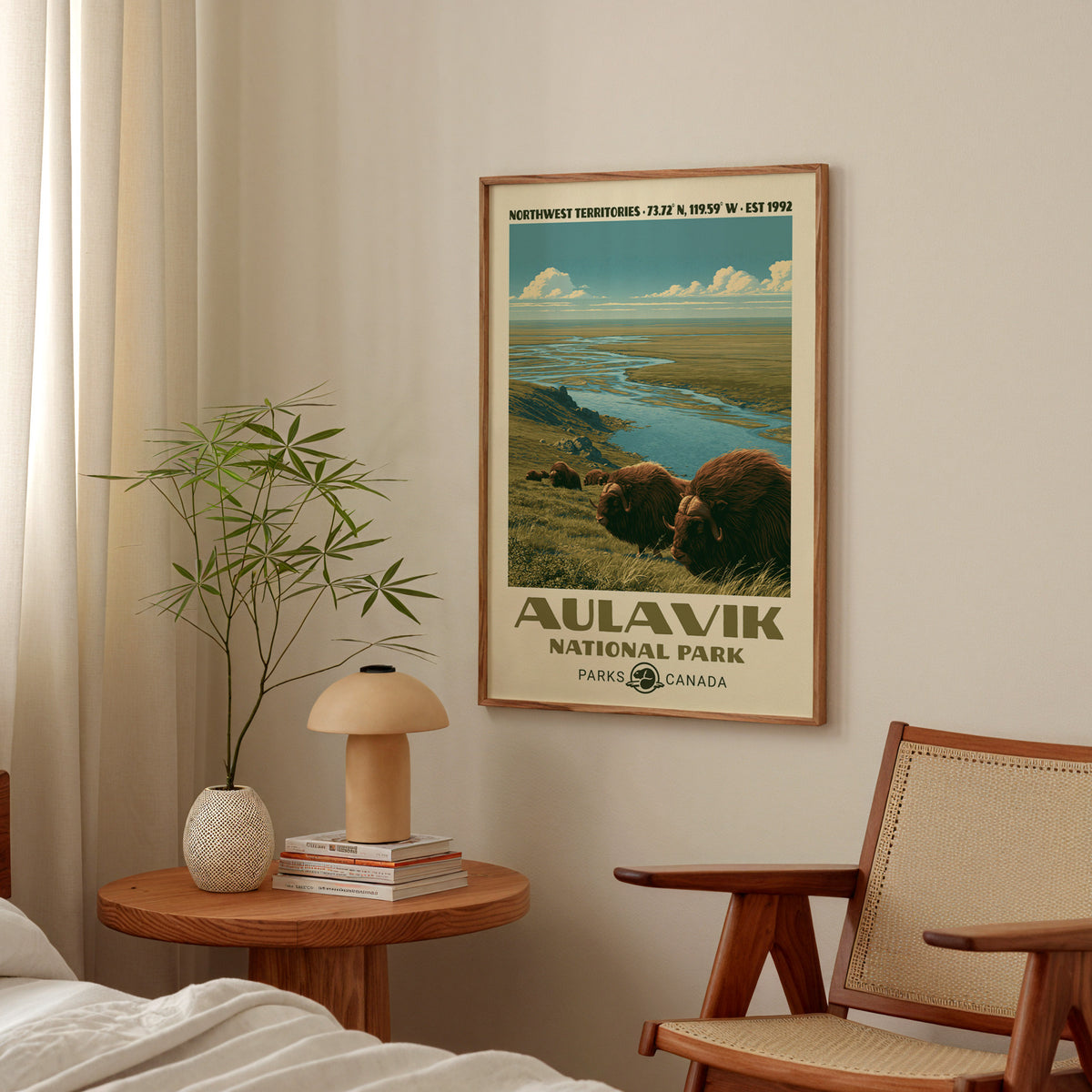 Aulavik National Park poster with Arctic muskoxen in an oak frame above a bedside table with a mushroom lamp