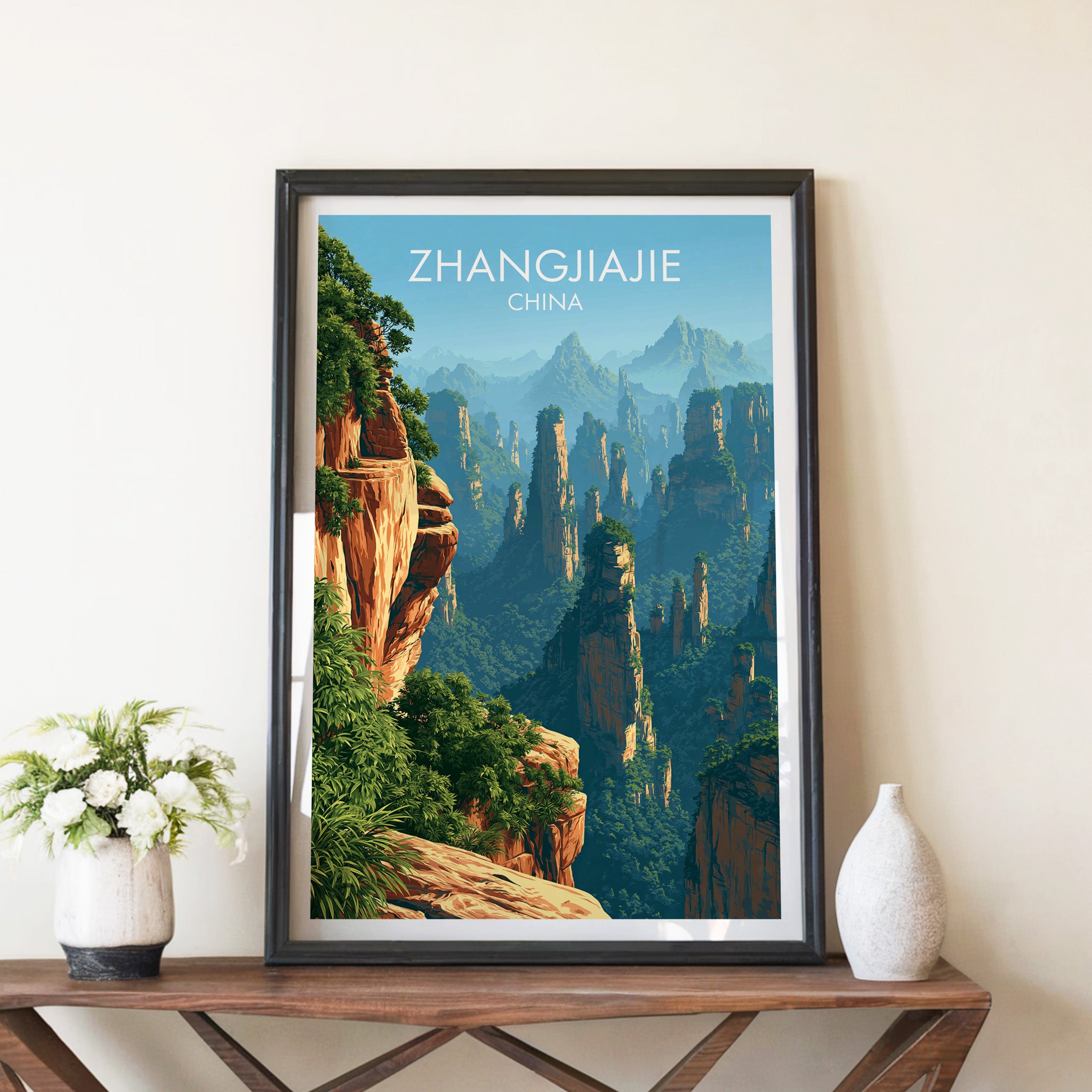 Zhangjiajie China travel poster in a black frame on a wooden console table with white flowers