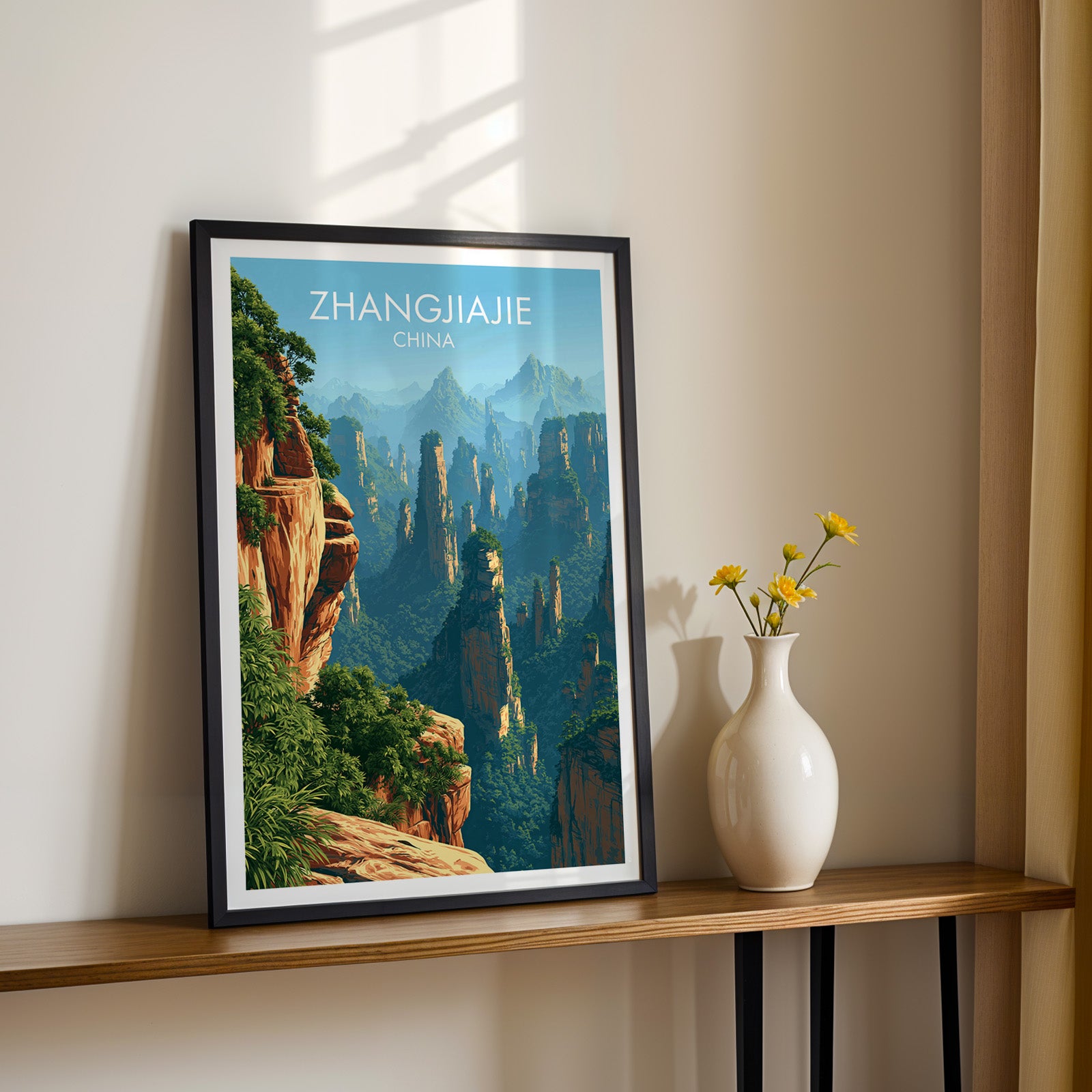 Black framed Zhangjiajie China print on a narrow hallway console in sunlight, styled with yellow flowers