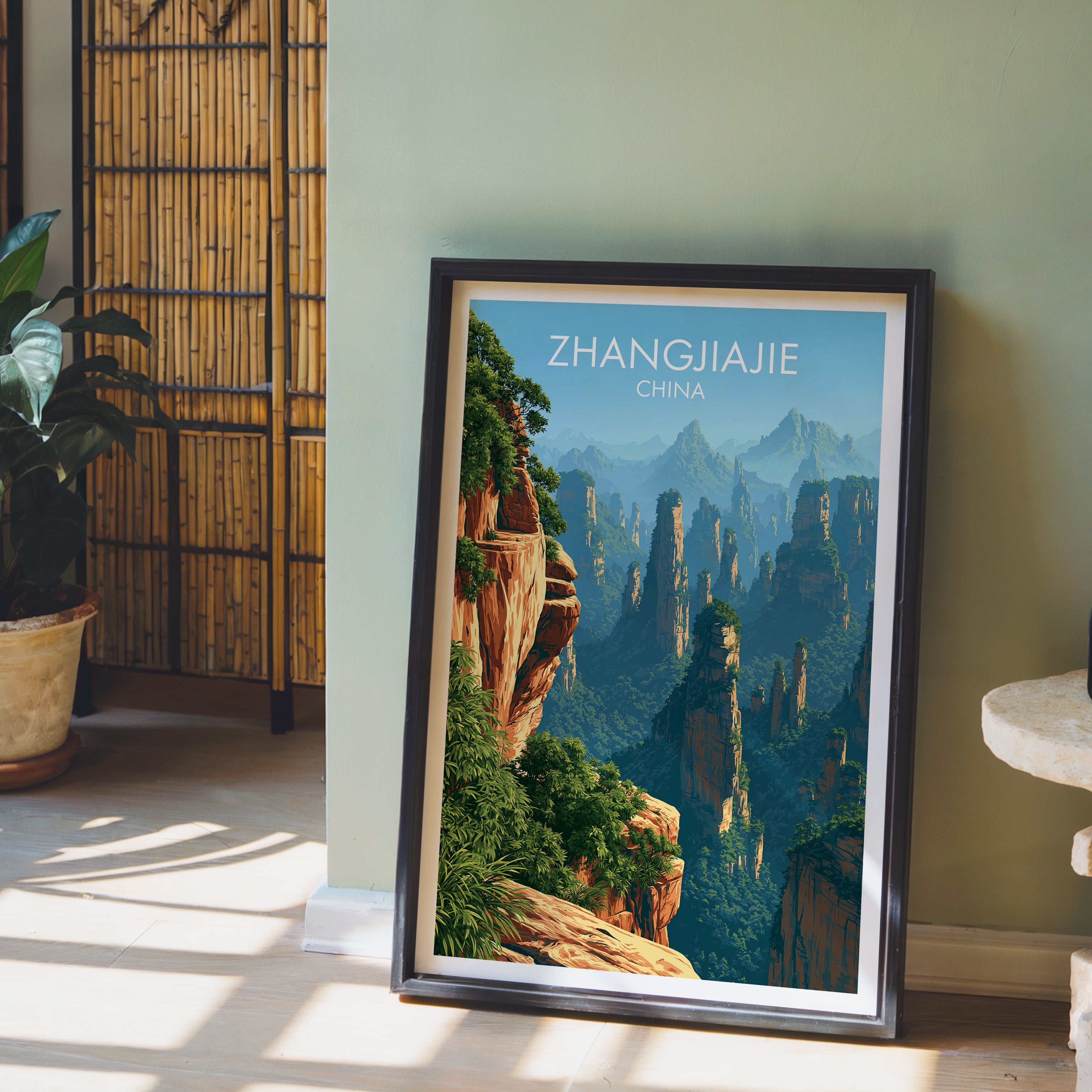 Zhangjiajie China wall art in a black frame leaning against a sage green wall beside a bamboo screen