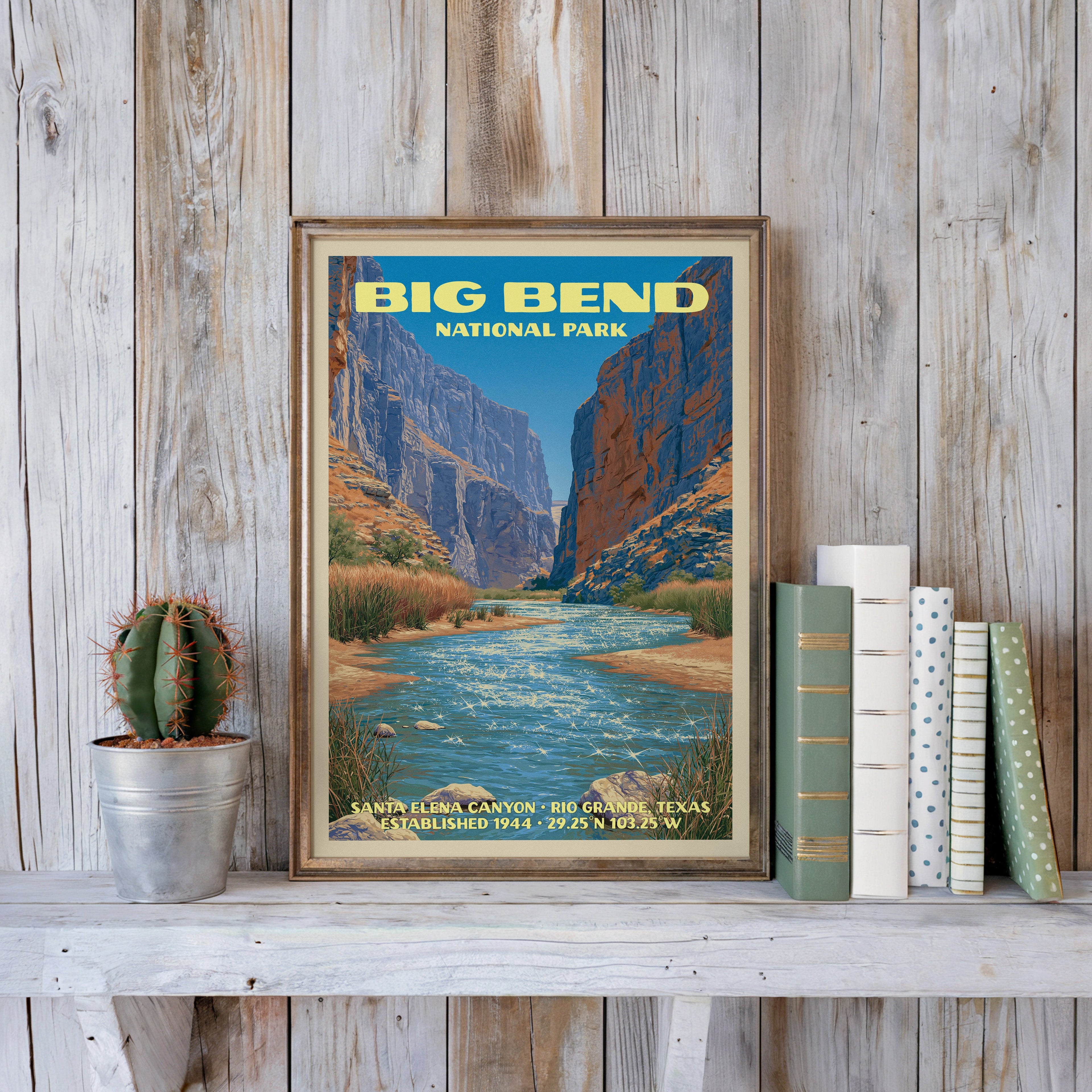 Big Bend vintage poster in a slim gold frame on a whitewashed plank wall beside a cactus and pastel books