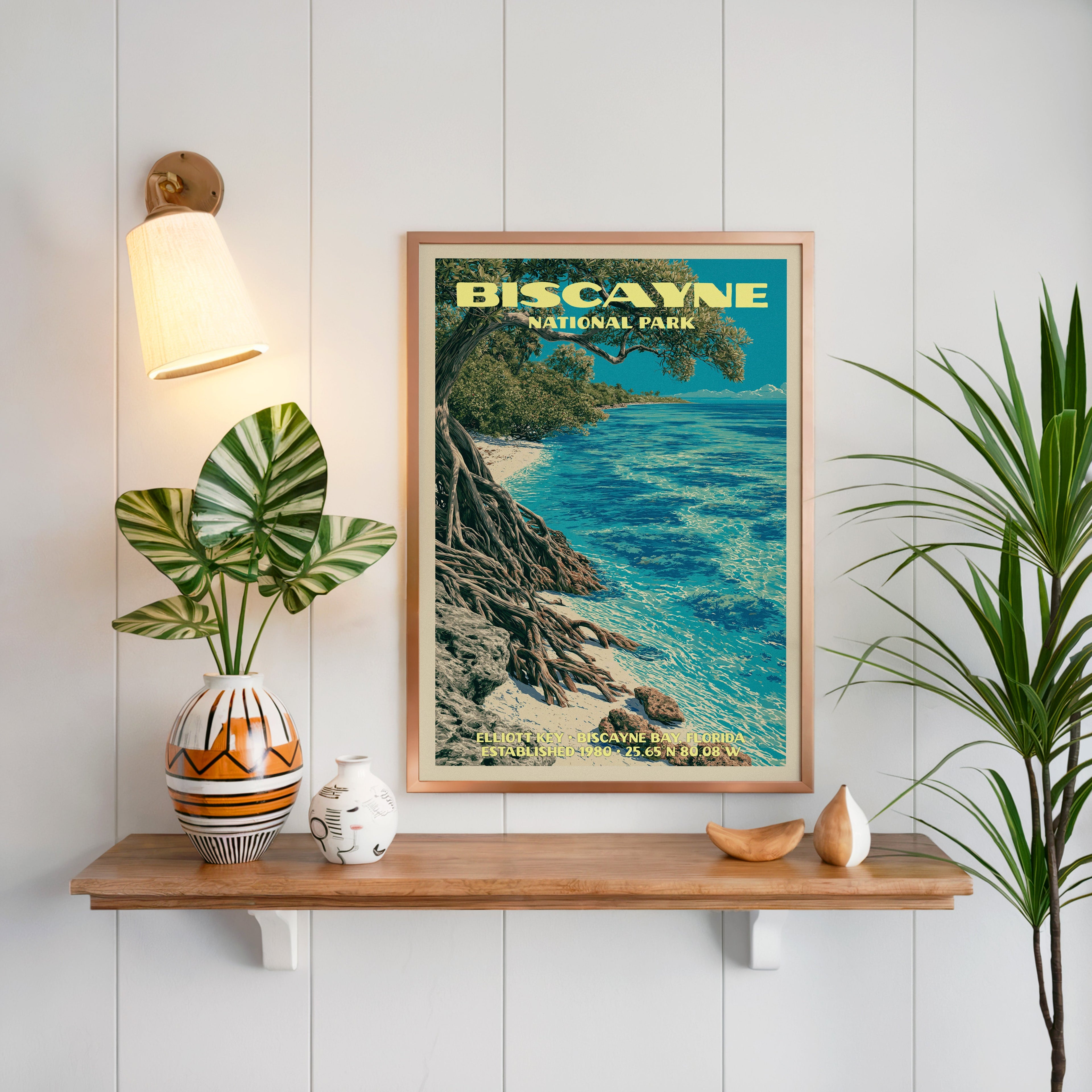 Elliott Key Biscayne print framed on white panelling above an oak shelf with a patterned vase and a sconce