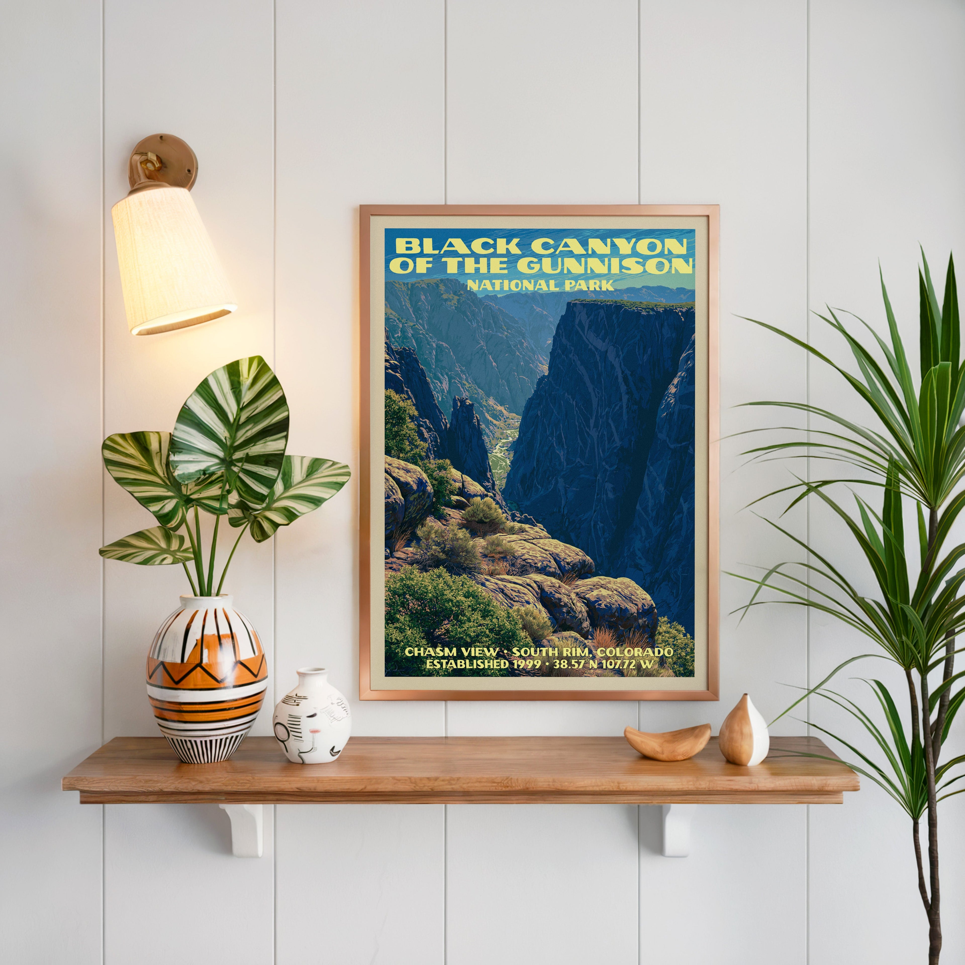 Chasm View Black Canyon print framed on white panelling above an oak shelf with a vase and a sconce