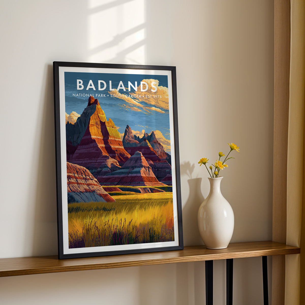 Badlands National Park mid-century modern art print in a slim black frame resting on a narrow console table beside a white vase of yellow blooms — hallway wall art