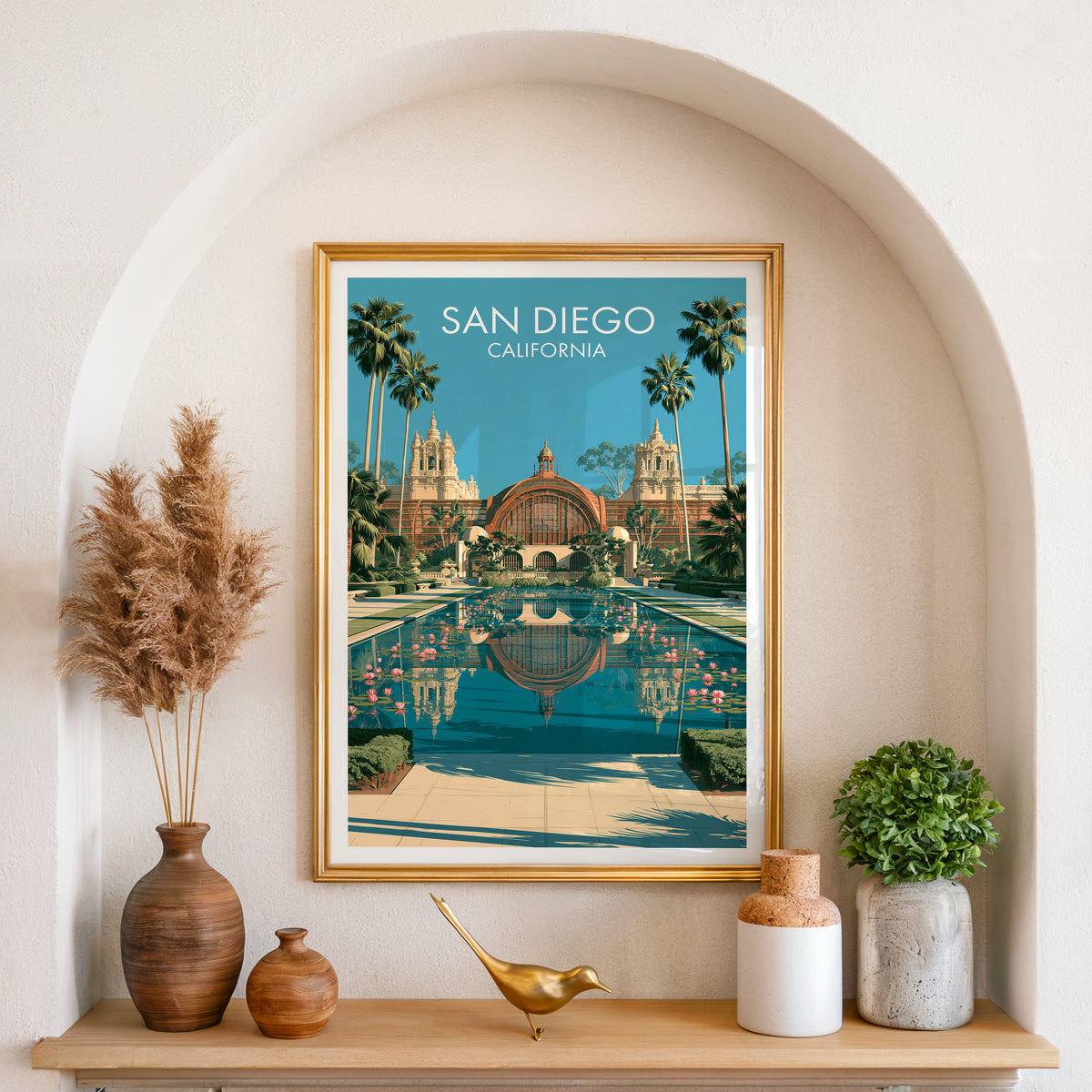 San Diego garden poster in a gold frame set into an arched alcove with pampas grass and a brass bird