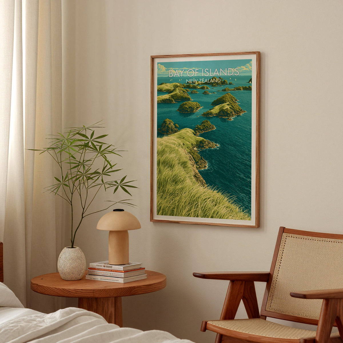 Teal bay artwork hung in a bedroom above a round bedside table with a mushroom lamp and bamboo stems