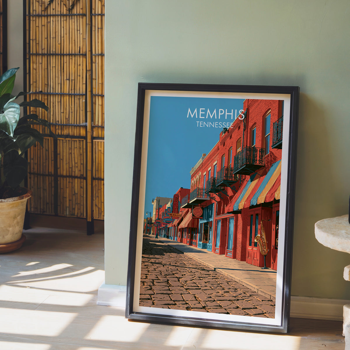 Beale Street print in a black frame on a sage green wall with a bamboo screen and an orchid in clay