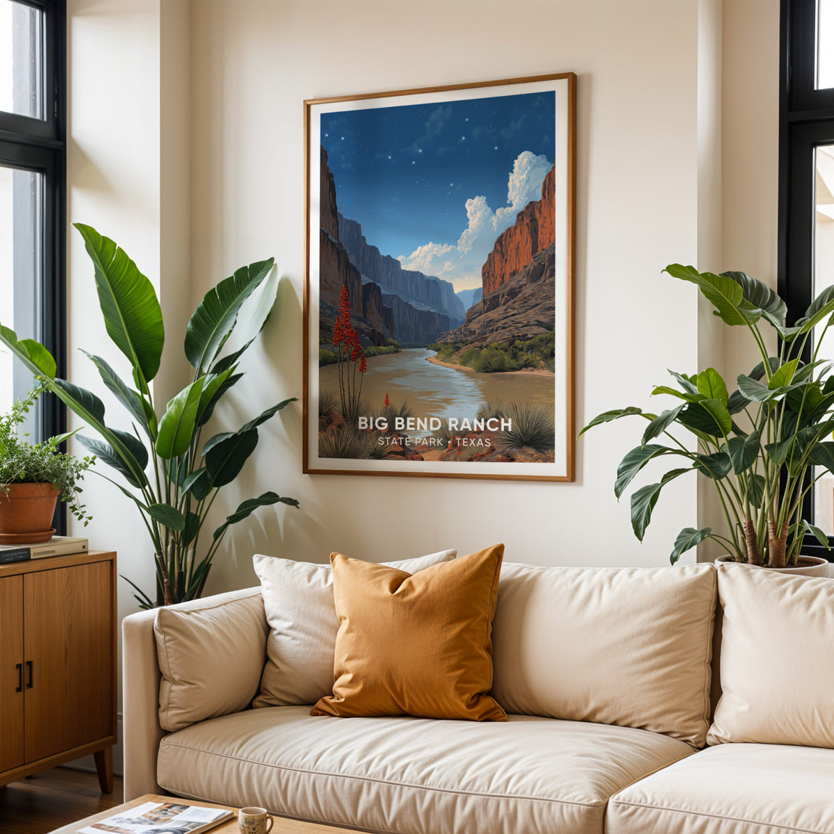 Big Bend Ranch wall art above a cream sofa with ochre cushions and two large tropical plants