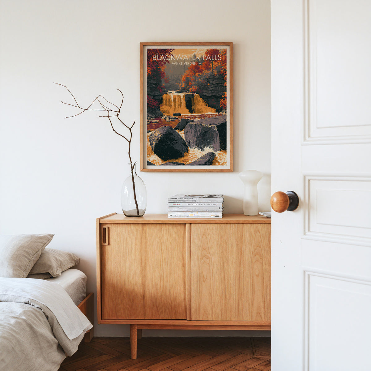 Blackwater Falls print in an oak frame on a light oak sideboard with dried stems and a white vase