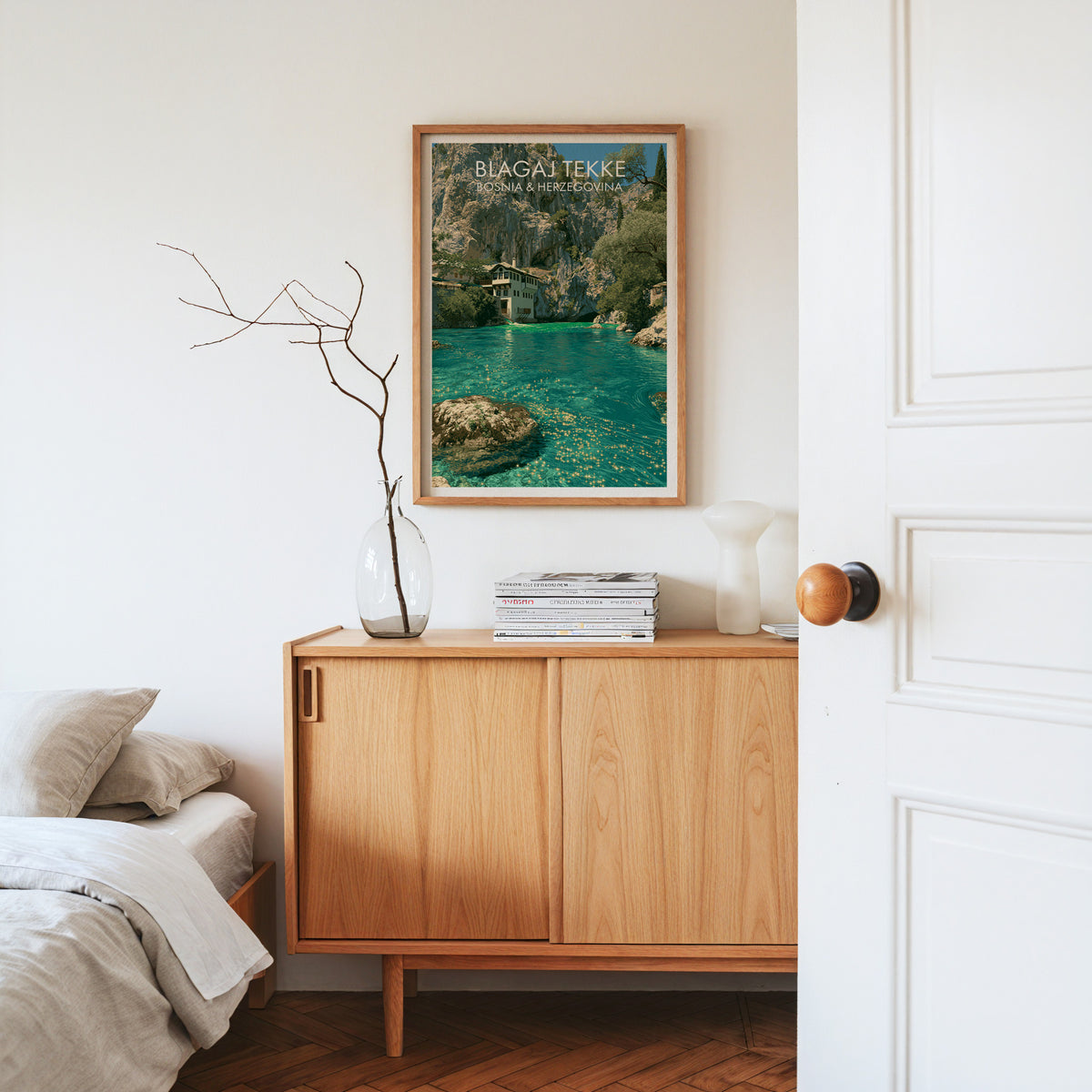 Blagaj cliff spring print, oak frame above a light oak sideboard with bare branches in a glass vase