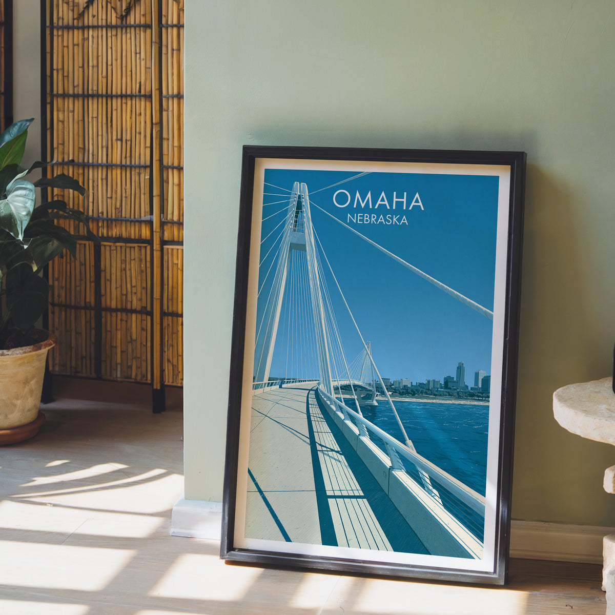Bob Kerrey Pedestrian Bridge print in a black frame by a sage wall, bamboo screen and potted orchid