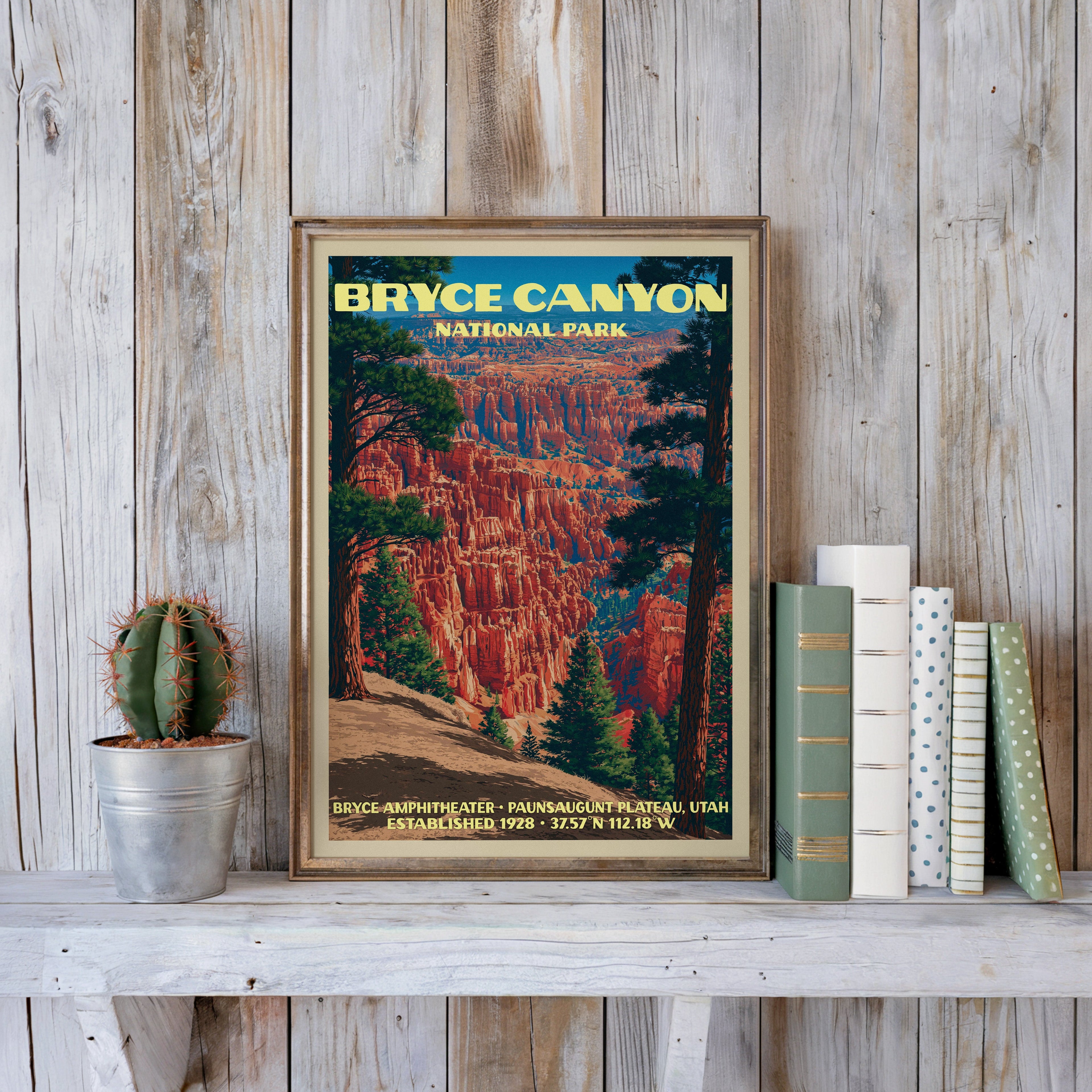 Bryce Canyon vintage poster in a slim gold frame on a whitewashed plank wall beside a cactus and books