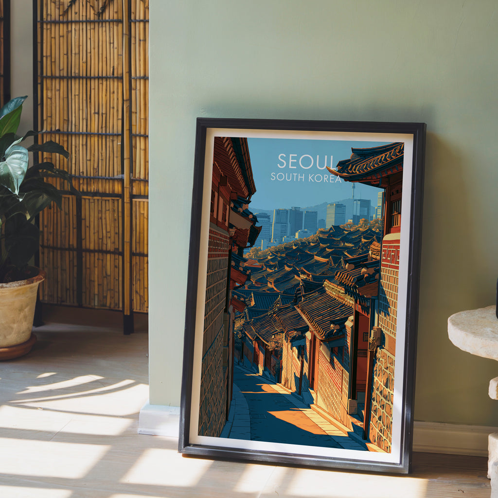 Bukchon Hanok Village Seoul wall art in a black frame leaning against a sage green wall beside a bamboo screen