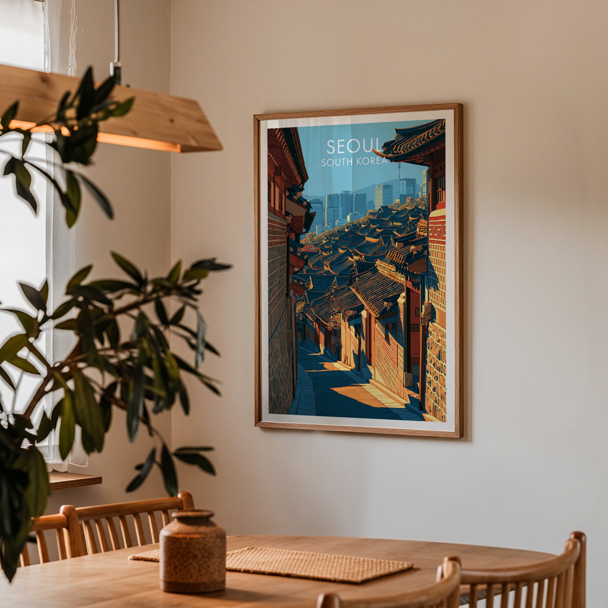 Framed Bukchon Hanok Village Seoul print on a dining room wall above an oak table in warm afternoon light