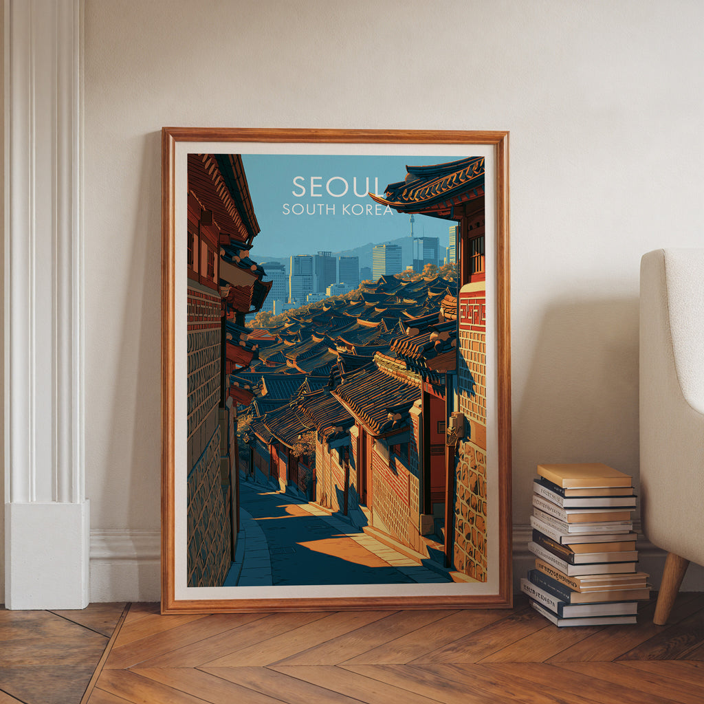 Bukchon Hanok Village Seoul art print in a walnut frame leaning in a hallway beside stacked books