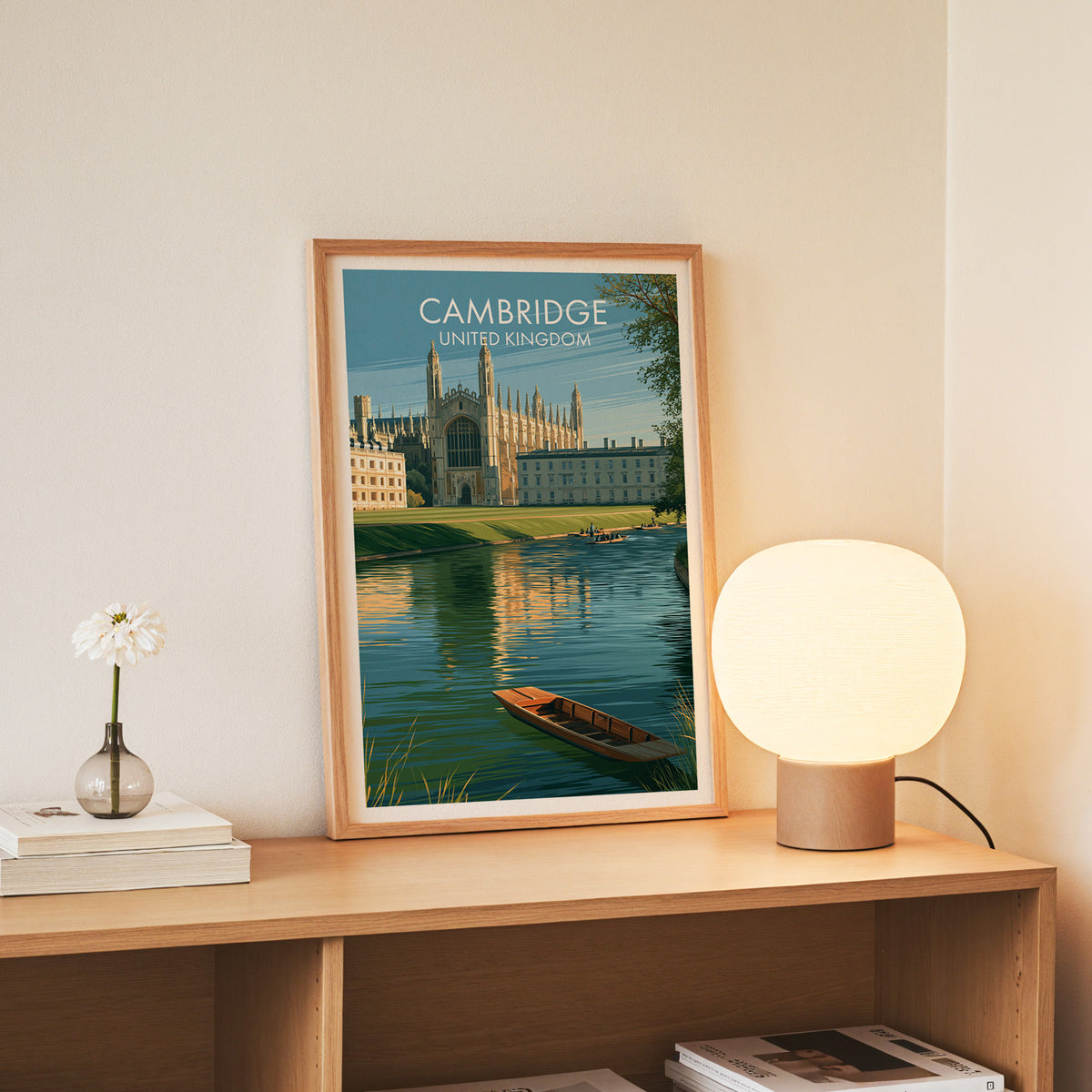 Cambridge college wall art, slim oak frame on an oak console beside a daisy in a glass bottle
