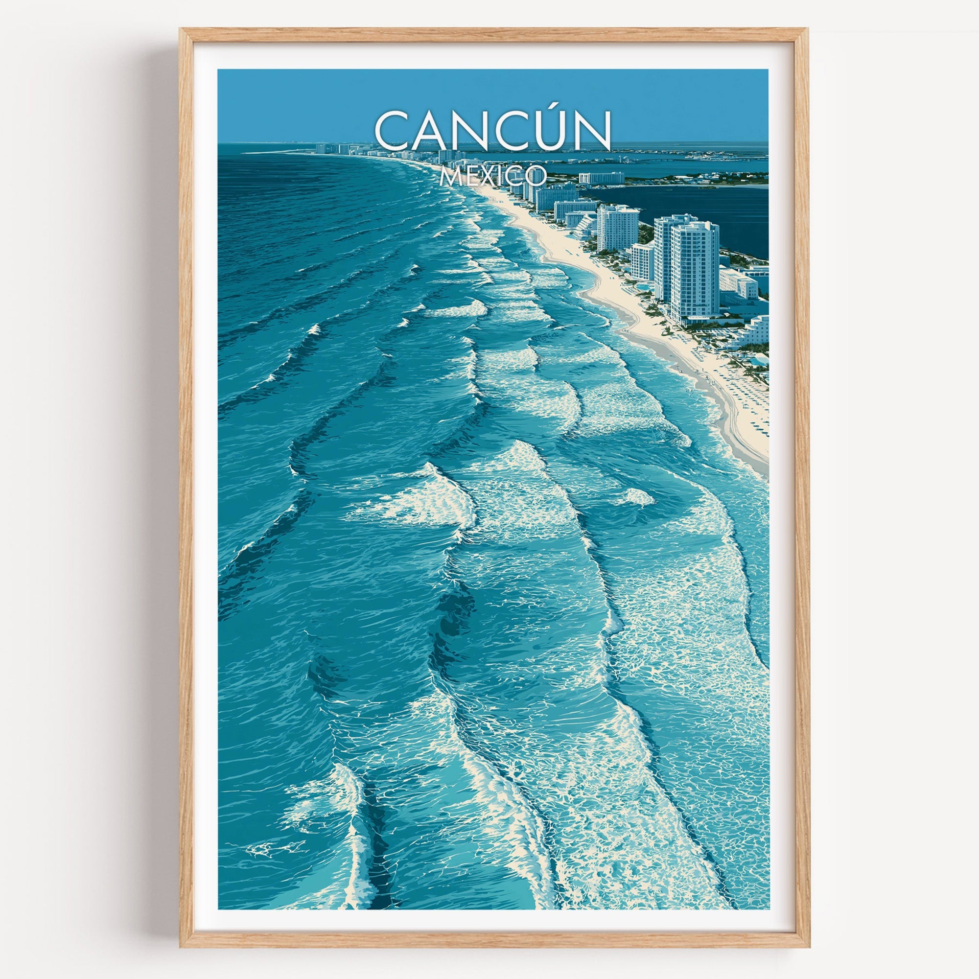 Cancun travel print of turquoise surf lines seen from above, in a light oak frame on a plain white wall.