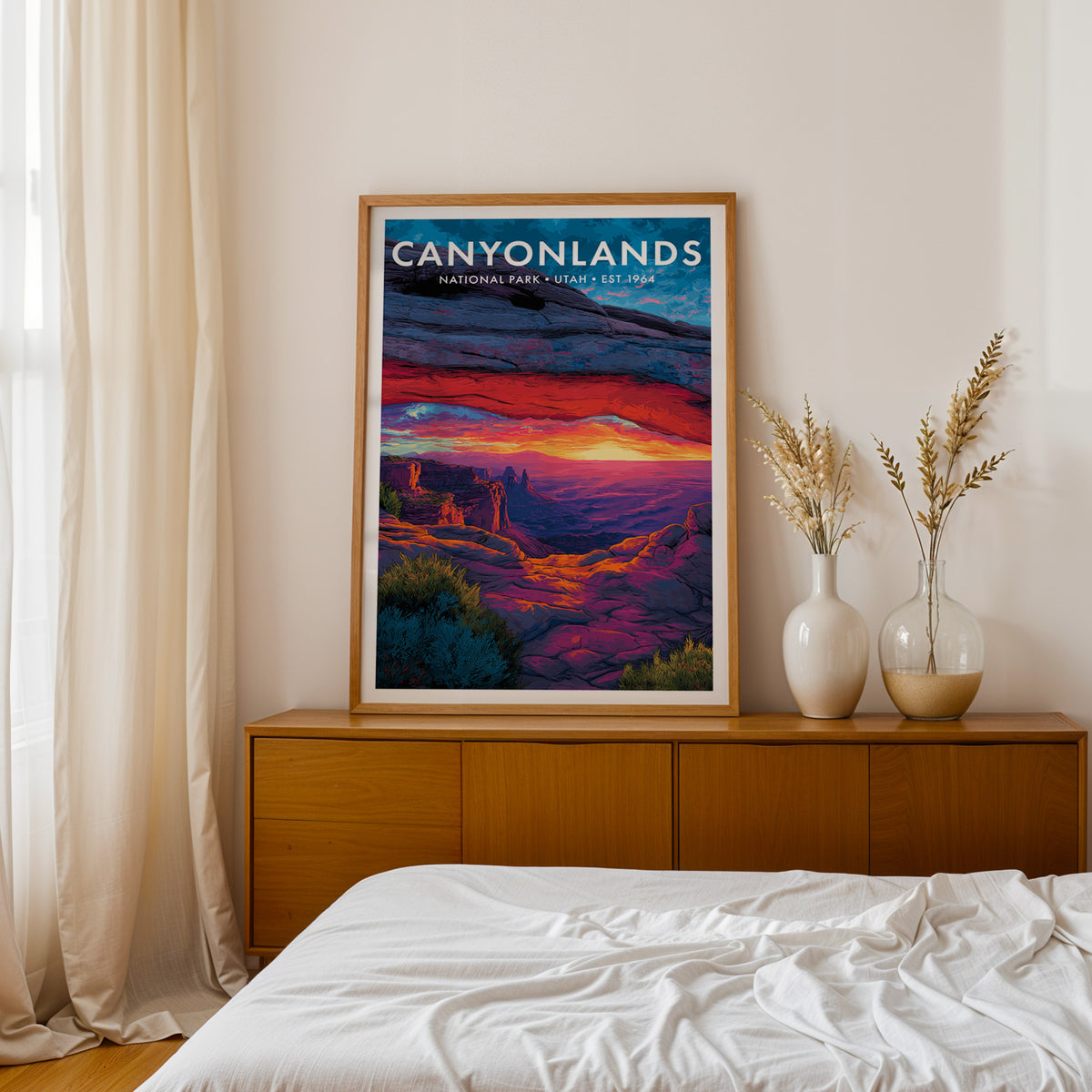 Canyonlands National Park mid-century modern art print framed in oak and propped on a mid-century walnut credenza beside a linen-dressed bed — bedroom wall art