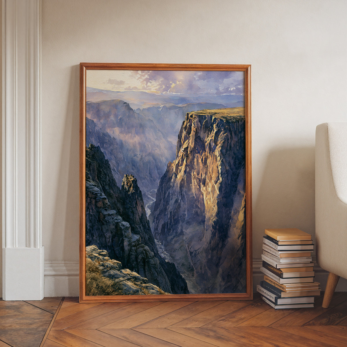 Black Canyon of the Gunnison watercolor print in a walnut frame leaning on a herringbone floor beside stacked books