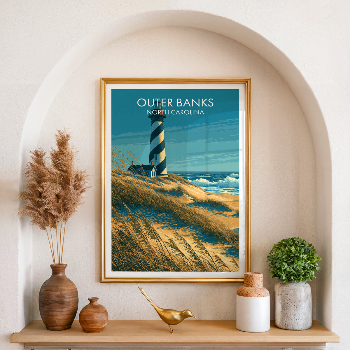 North Carolina dune wall art in a gold frame in an arched alcove with pampas grass and a shelf