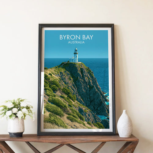 Byron Bay lighthouse poster in a black frame on a walnut console with white peonies and a tall stone vase