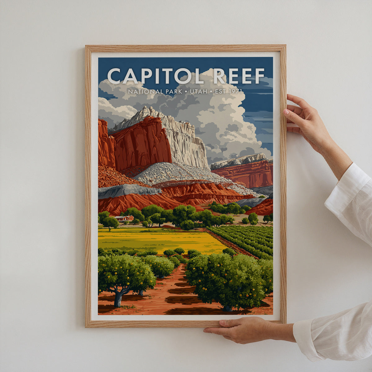 Capitol Reef National Park mid-century modern art print in a light oak frame being hung on a bright white wall