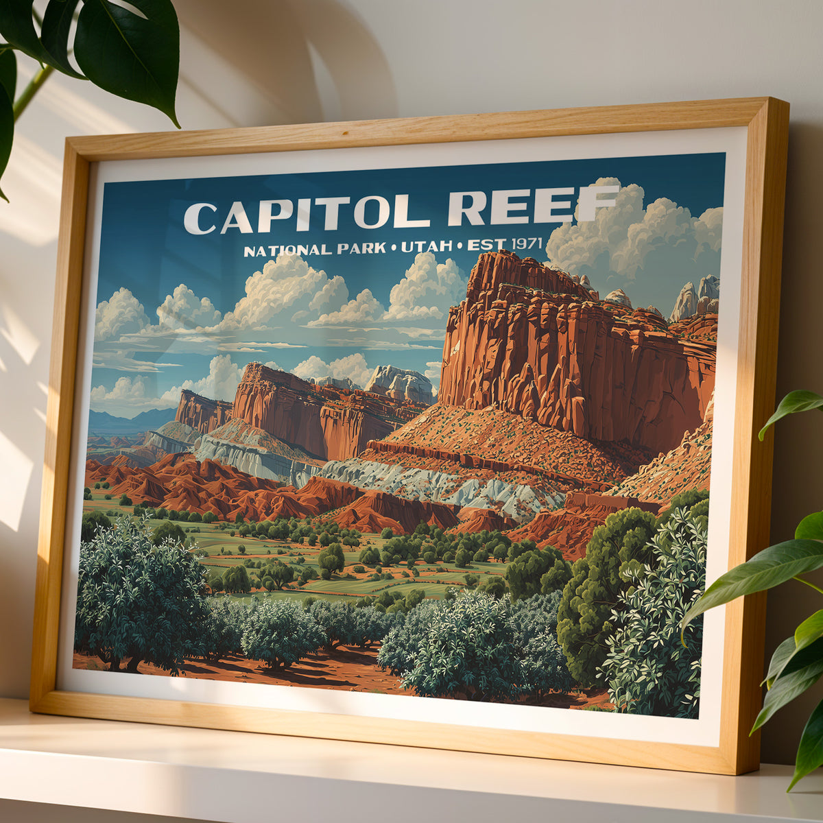 Capitol Reef National Park wall art print in a light oak frame, leaning on a white shelf in warm sunlight beside a monstera plant