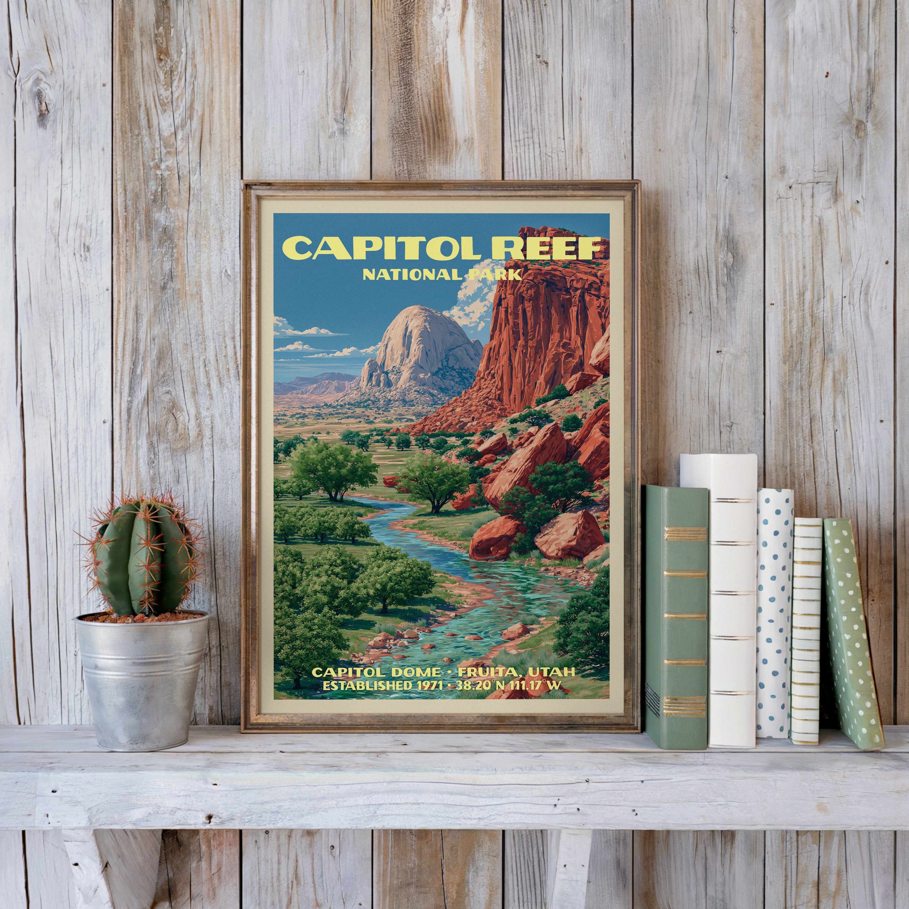 Capitol Reef vintage poster in a slim gold frame on a whitewashed plank wall beside a cactus and pastel books