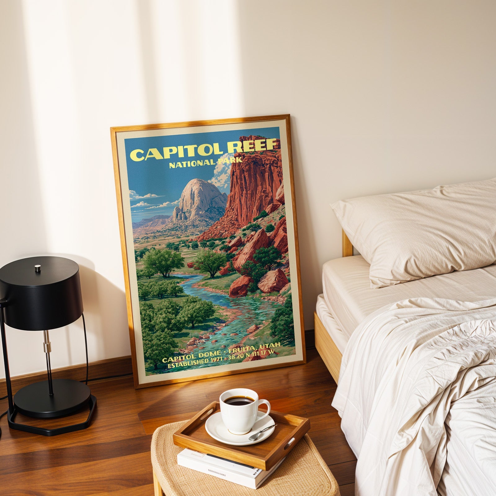 Capitol Dome Capitol Reef poster in a gold frame on the floor beside a made bed and a black table lamp