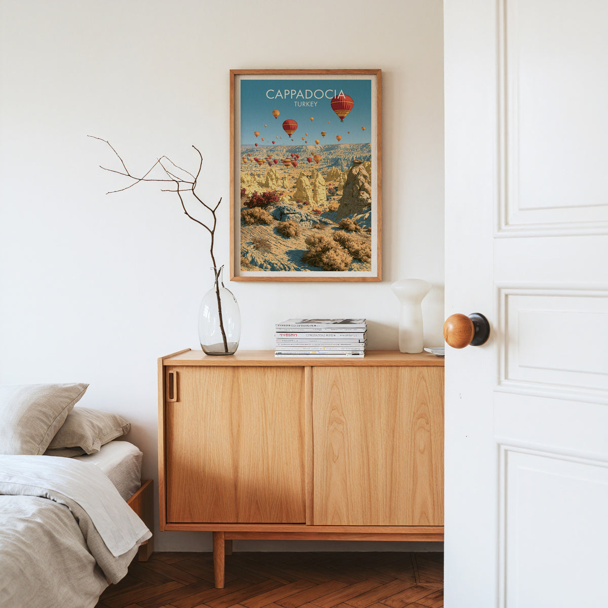 Cappadocia balloons print, oak frame above a light oak sideboard with bare branches in a glass vase