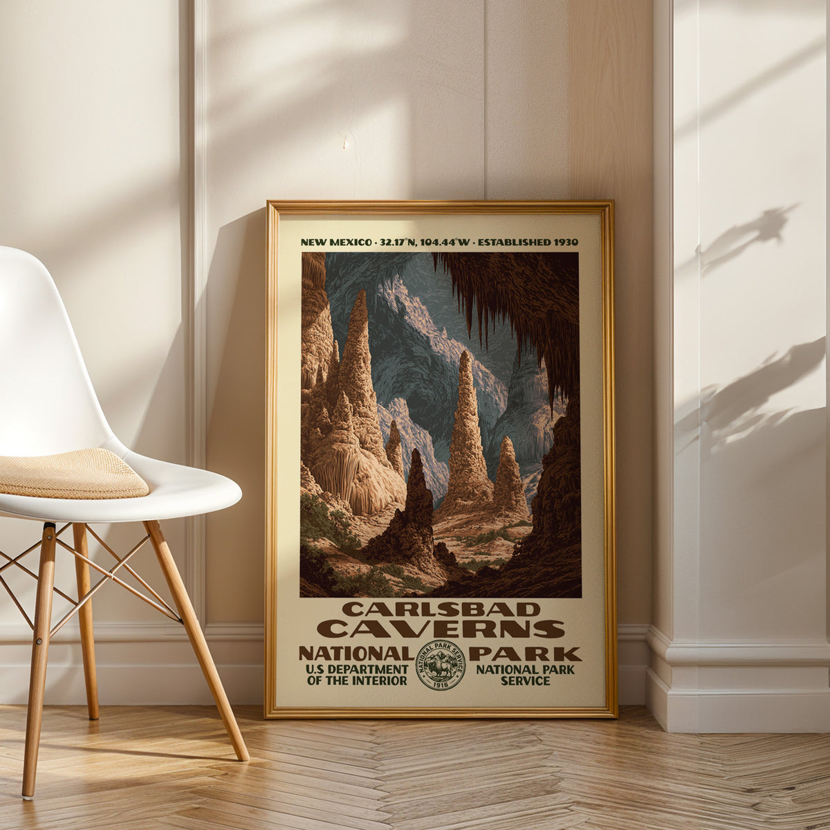 Carlsbad Caverns National Park vintage WPA art in an oak frame leaning by a white chair on a wood floor